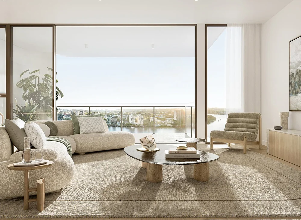 Modern living room with large glass sliding doors opening to a balcony overlooking a river and cityscape, furnished with a neutral-colored sectional sofa, a round stone coffee table, a striped lounge chair, and side tables, decorated with plants, pil