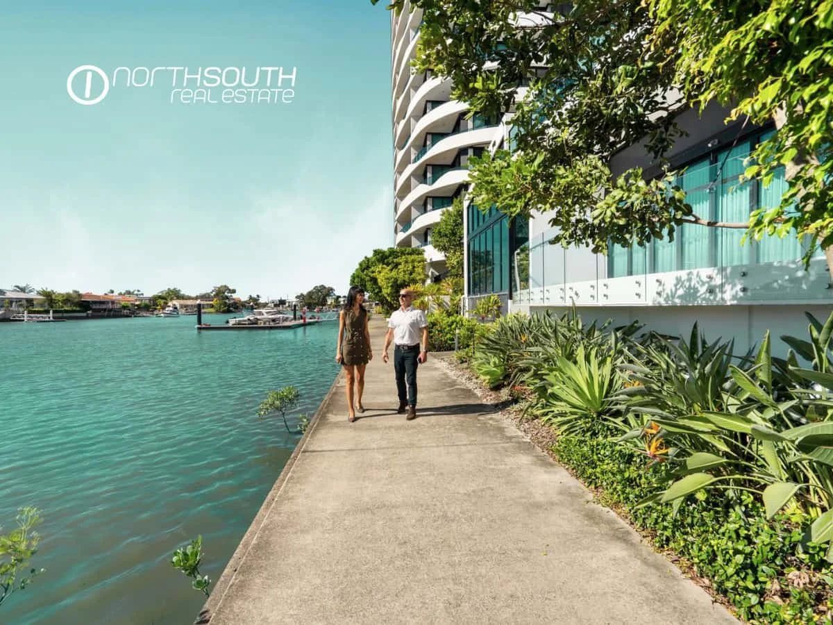 A couple walking along the canal walk at Waterpoint Residences, 5 Harbourside Ct Biggera Waters QLD. 