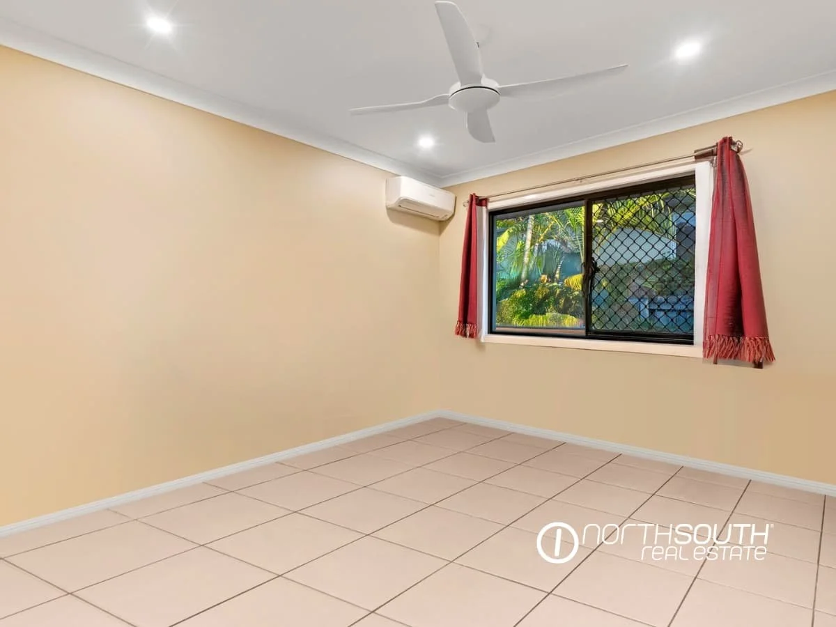 Third bedroom with light yellow wall paint, a ceiling fan, red curtains, air-conditioning unit and tiled floors at 7 Bligh Street, Rochedale South QLD 4123