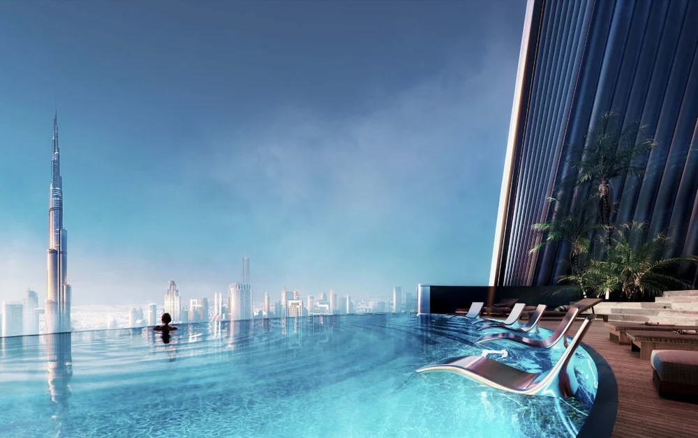 A person relaxing in an infinity pool on a rooftop overlooking a city skyline, including the Burj Khalifa, under a clear blue sky.
