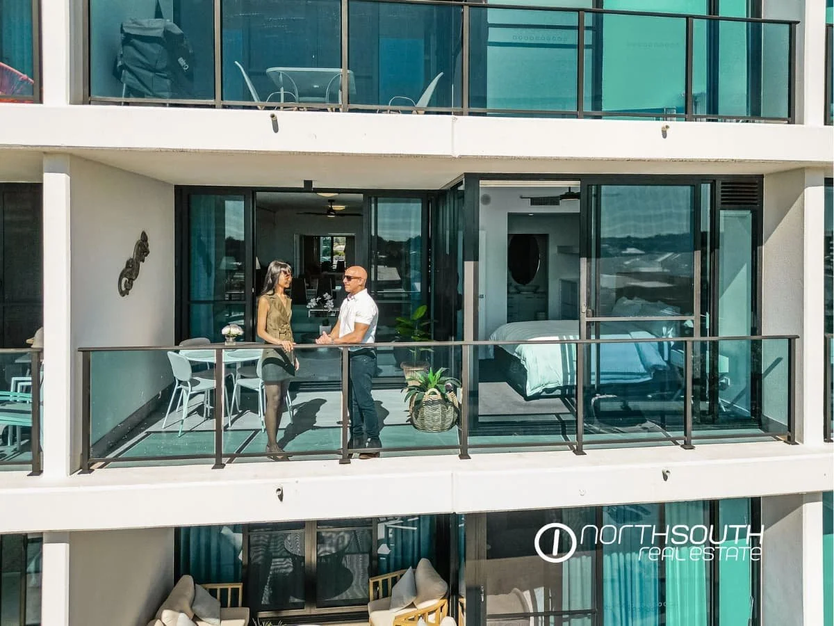A couple standing on the balcony of apartment 3303 in Waterpoint Residences, Biggera Waters QLD.