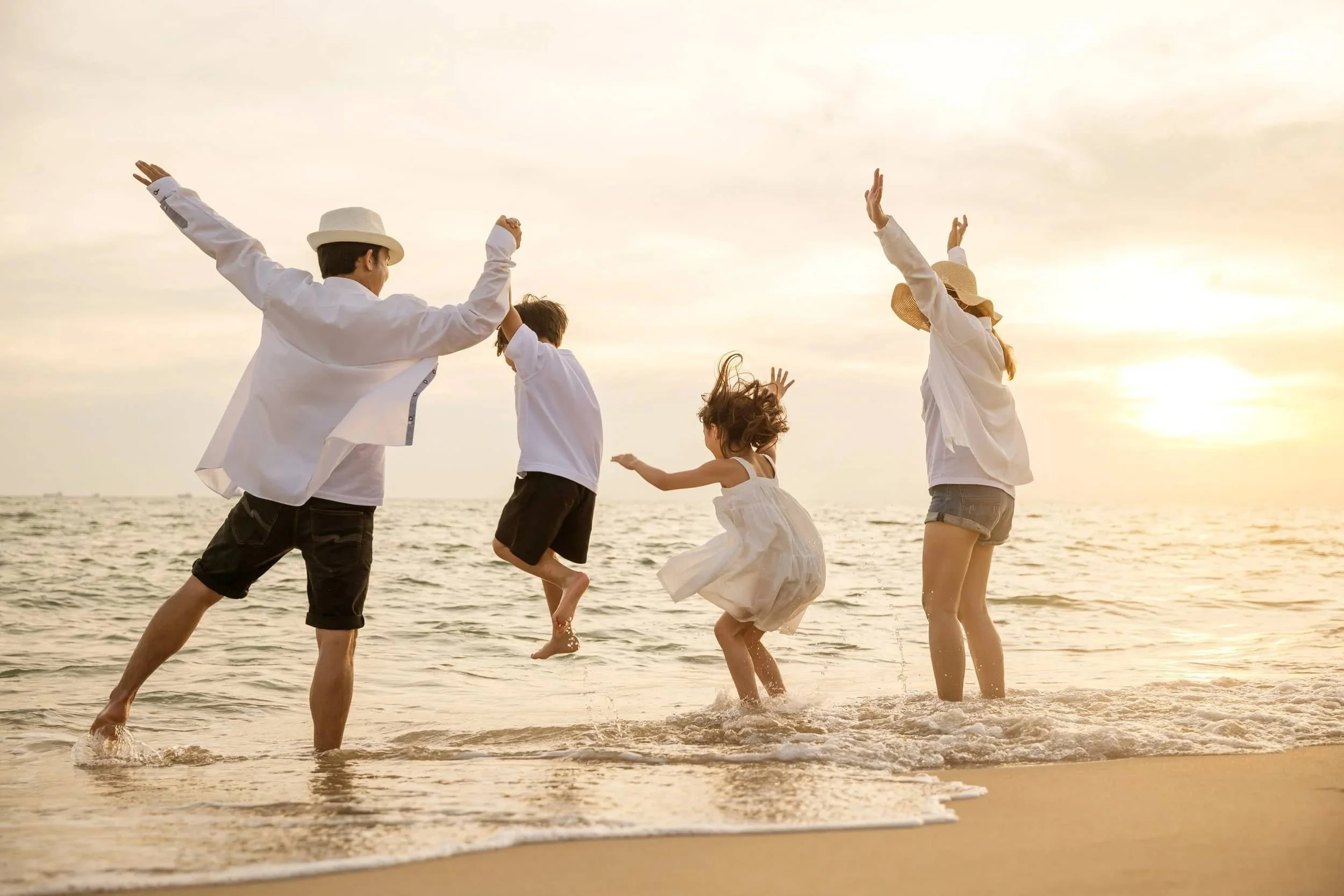 A relaxed family enjoying a sunset together on the beach, playing in the water.