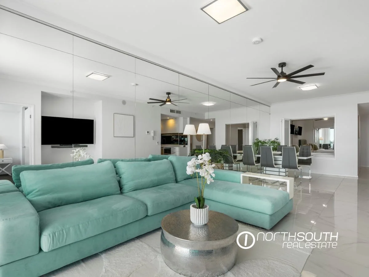 Living room with a lounge and mirrored wall at 3303/5 Harbourside Ct Waterpoint Residences, Biggera Waters QLD.