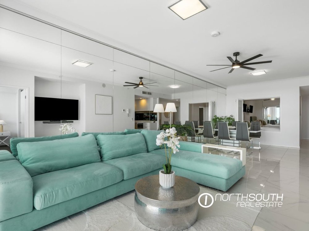 Living room with a lounge and mirrored wall at 3303/5 Harbourside Ct Waterpoint Residences, Biggera Waters QLD.