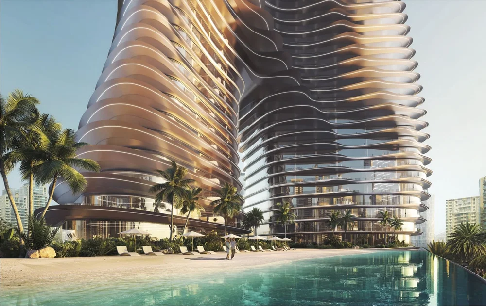 Modern high-rise building with curving balconies, palm trees, and a pool area in front, set against a cityscape background.