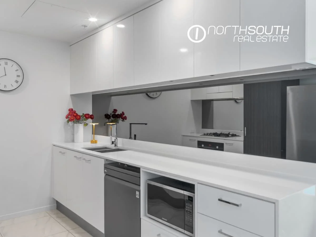 Kitchen with mirrored splashback, dishwasher and microwave at  3409/5 Harbourside Ct Waterpoint Residences, Biggera Waters QLD.