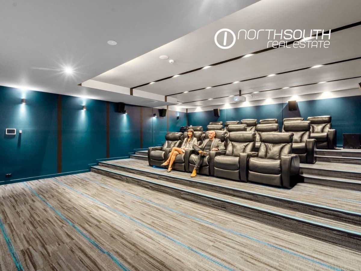 A couple watching a movie in a private cinema with 16 leather reclining chairs at Waterpoint Residences, Biggera Waters QLD.
