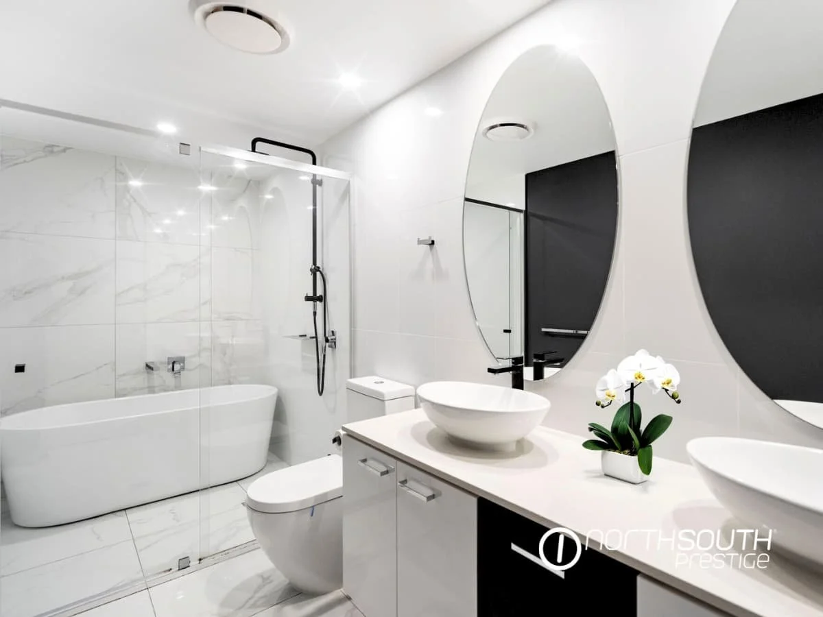 Contemporary ensuite with freestanding bath, twin vanities, and tiled floors at Waterpoint Residences, Biggera Waters QLD.