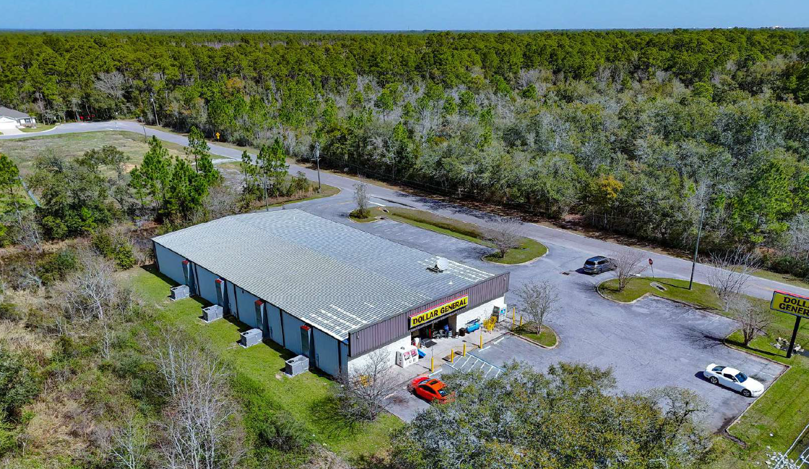 An aerial view of a Dollar General store surrounded by parking lot and trees.