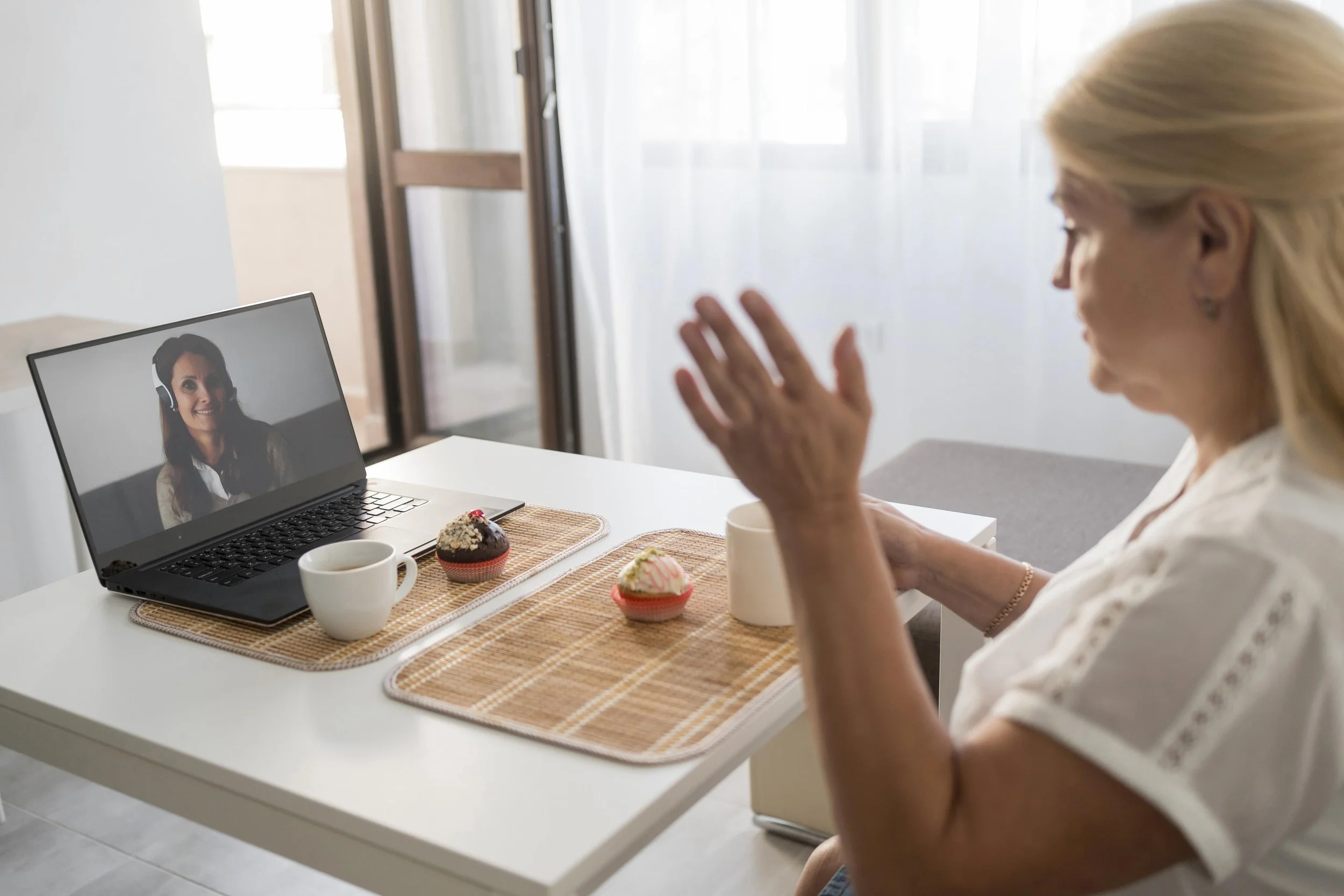 Woman sitting on chair having a drink with friend on laptop
