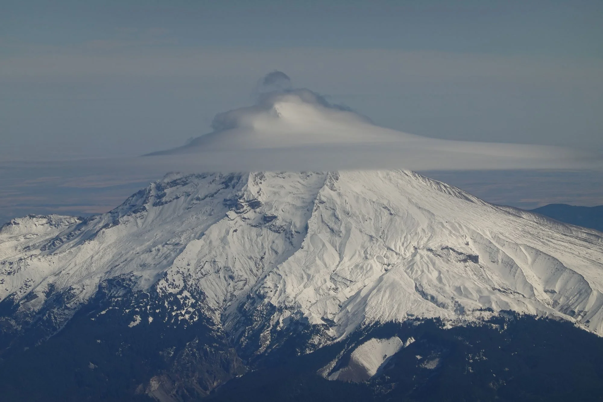 Rocky snow-capped mountain with a cloud at the top
