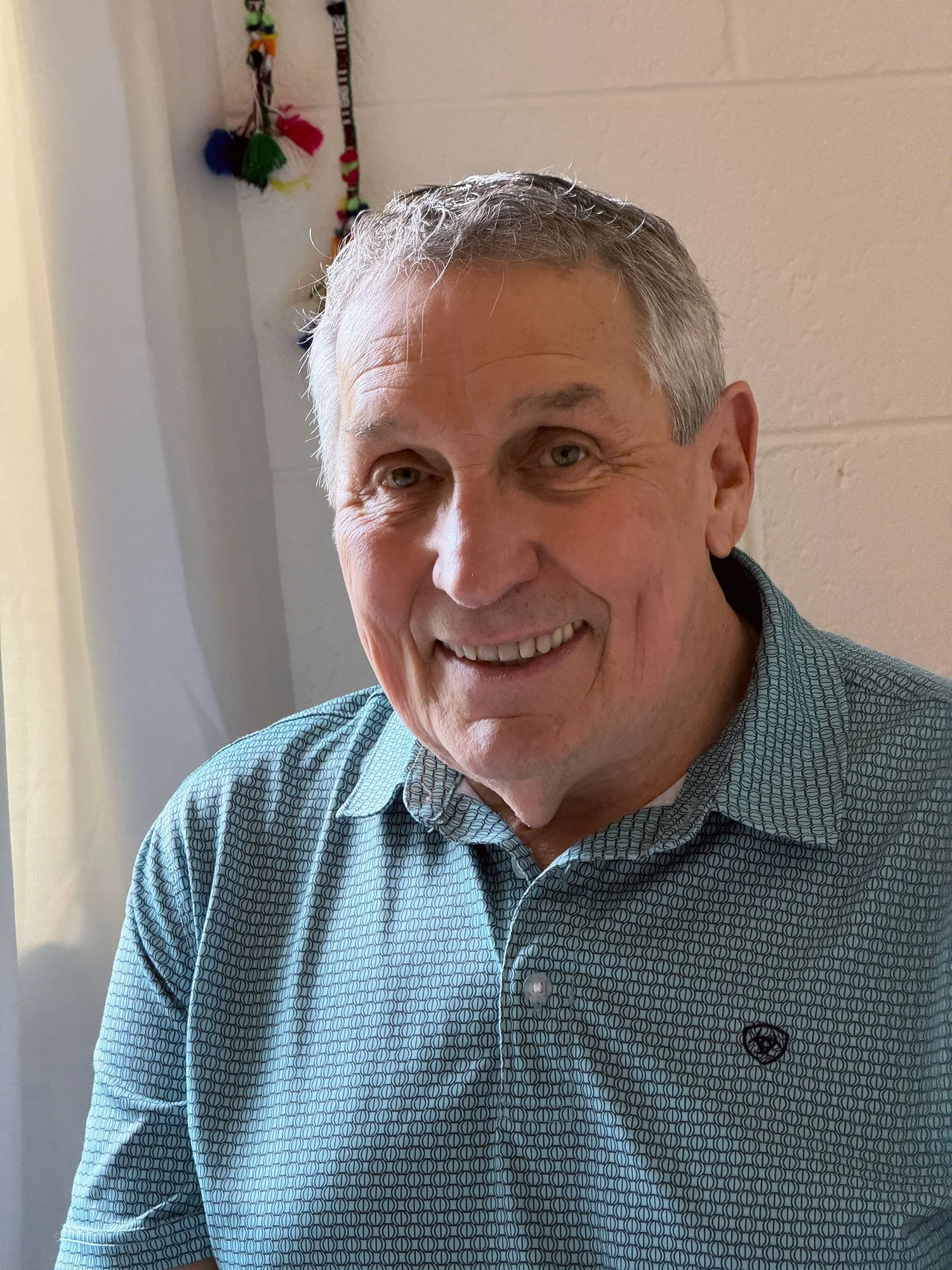 Roger Wheelock of Community Shaman smiling in front of a white wall