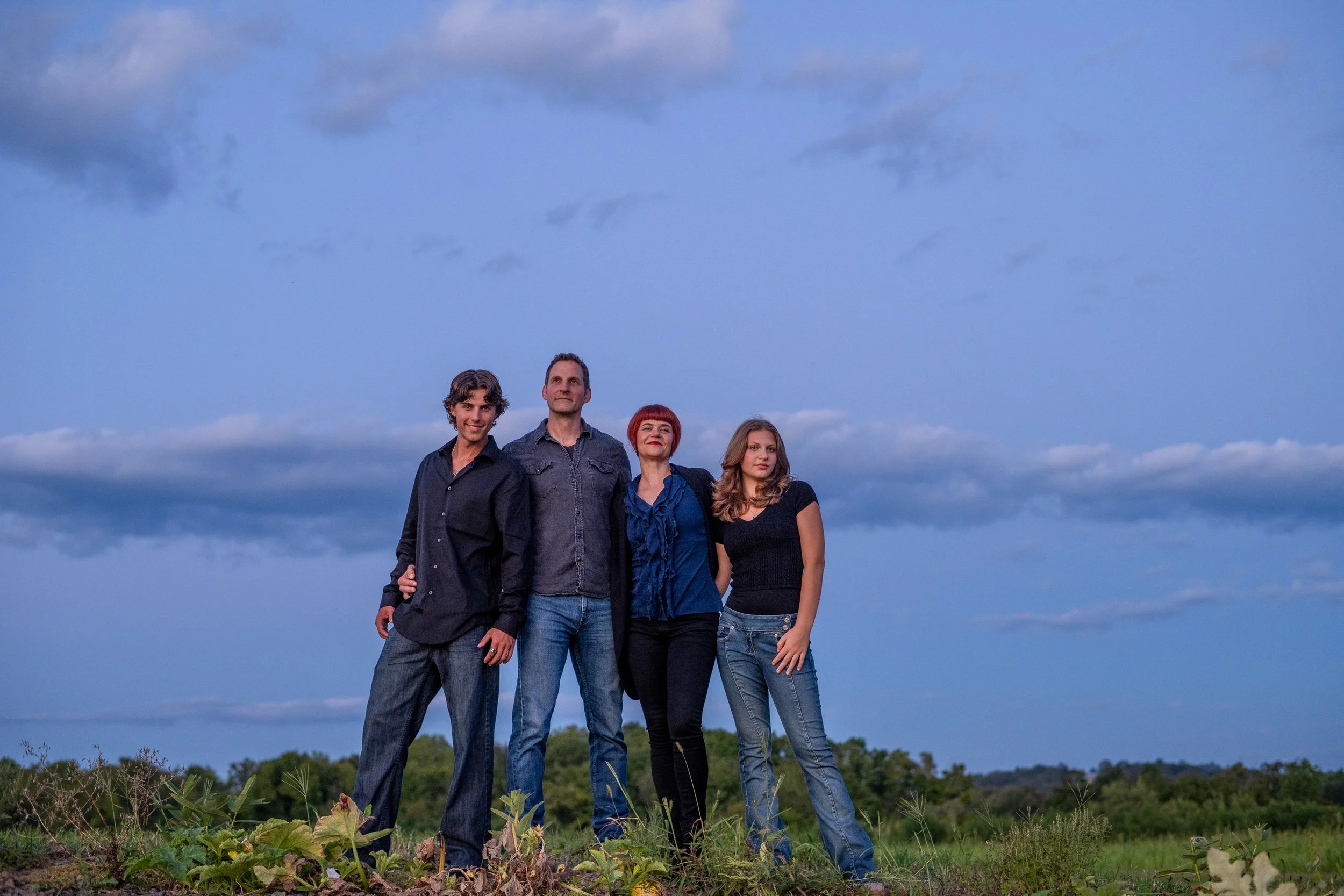 Portrait Session in golden light at Greig Farm. A family at the top of the hill with mostly sky showing as the background.