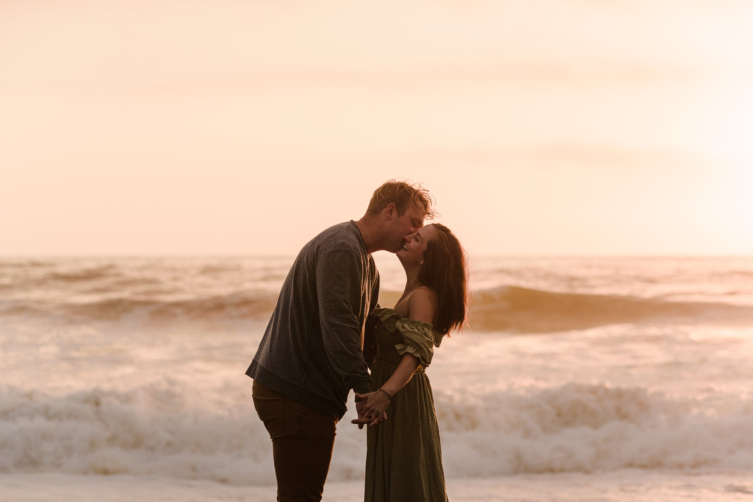 man kissing woman on the cheek with the ocean in the background