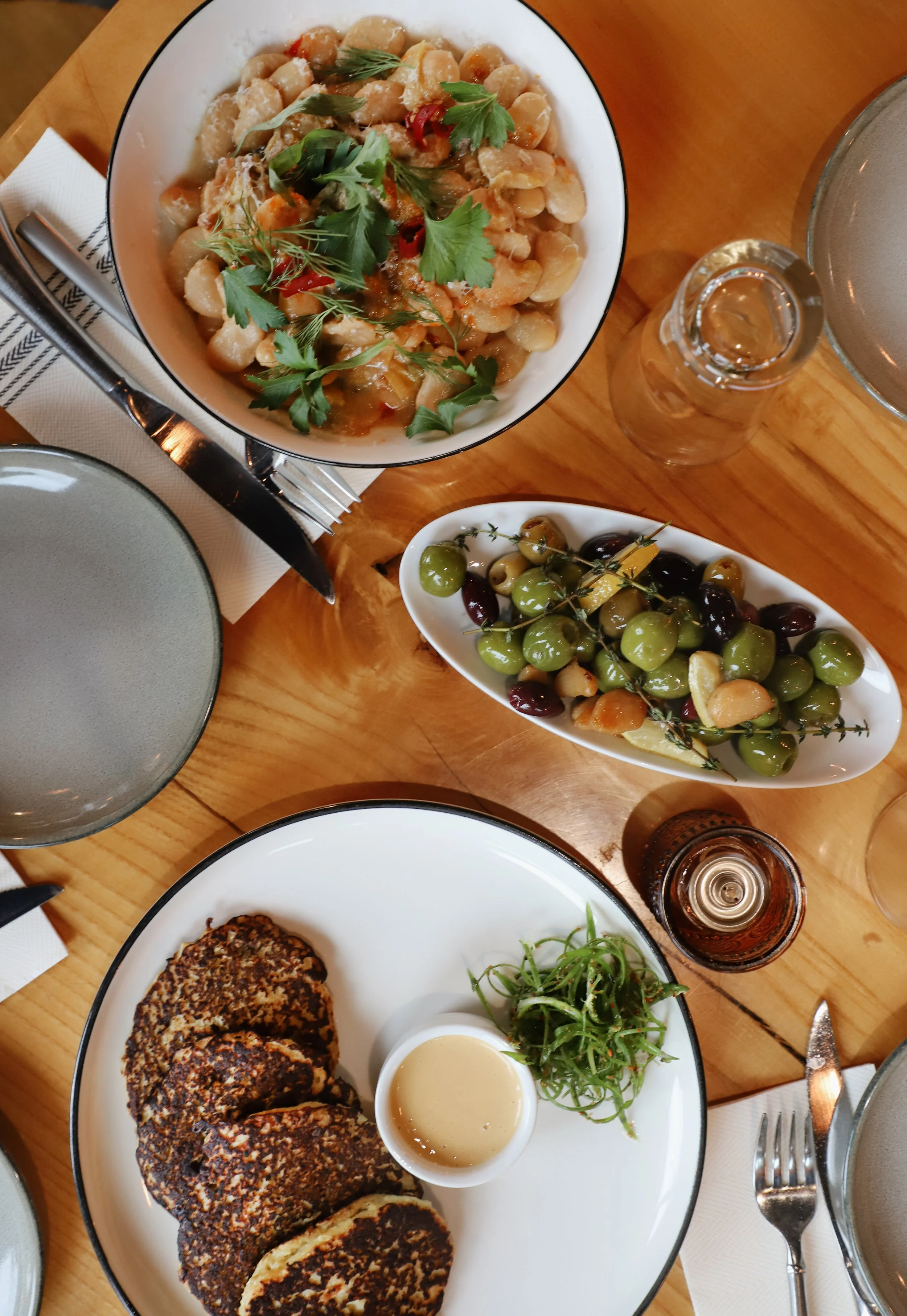 tablescape of tapas dishes on carnegie cellars table with wine glasses, olives, beans, and other locally sourced foods