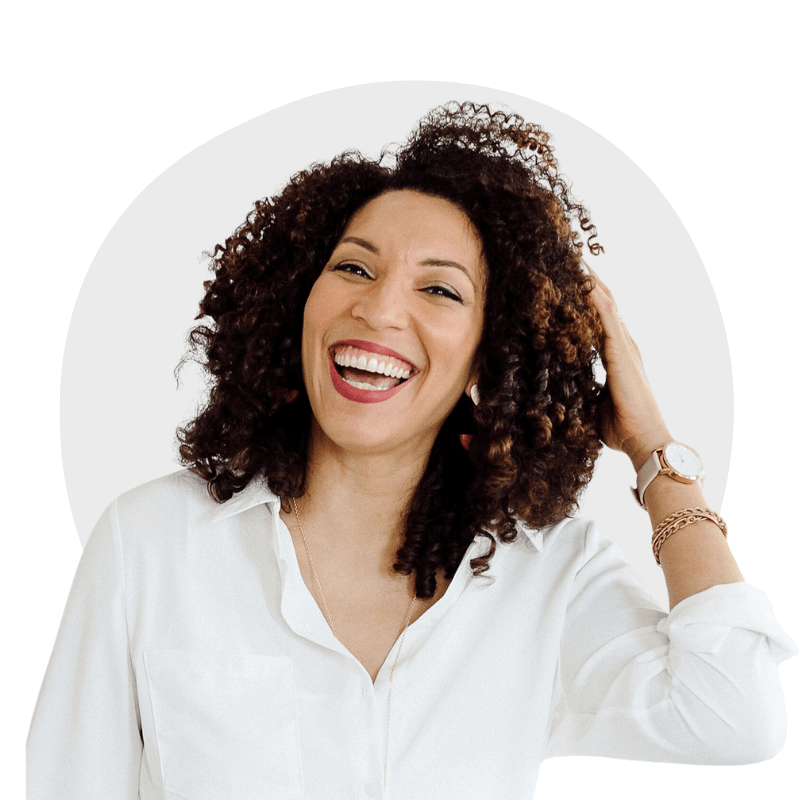 Woman with curly hair smiling, wearing a white shirt and watch, touching her hair