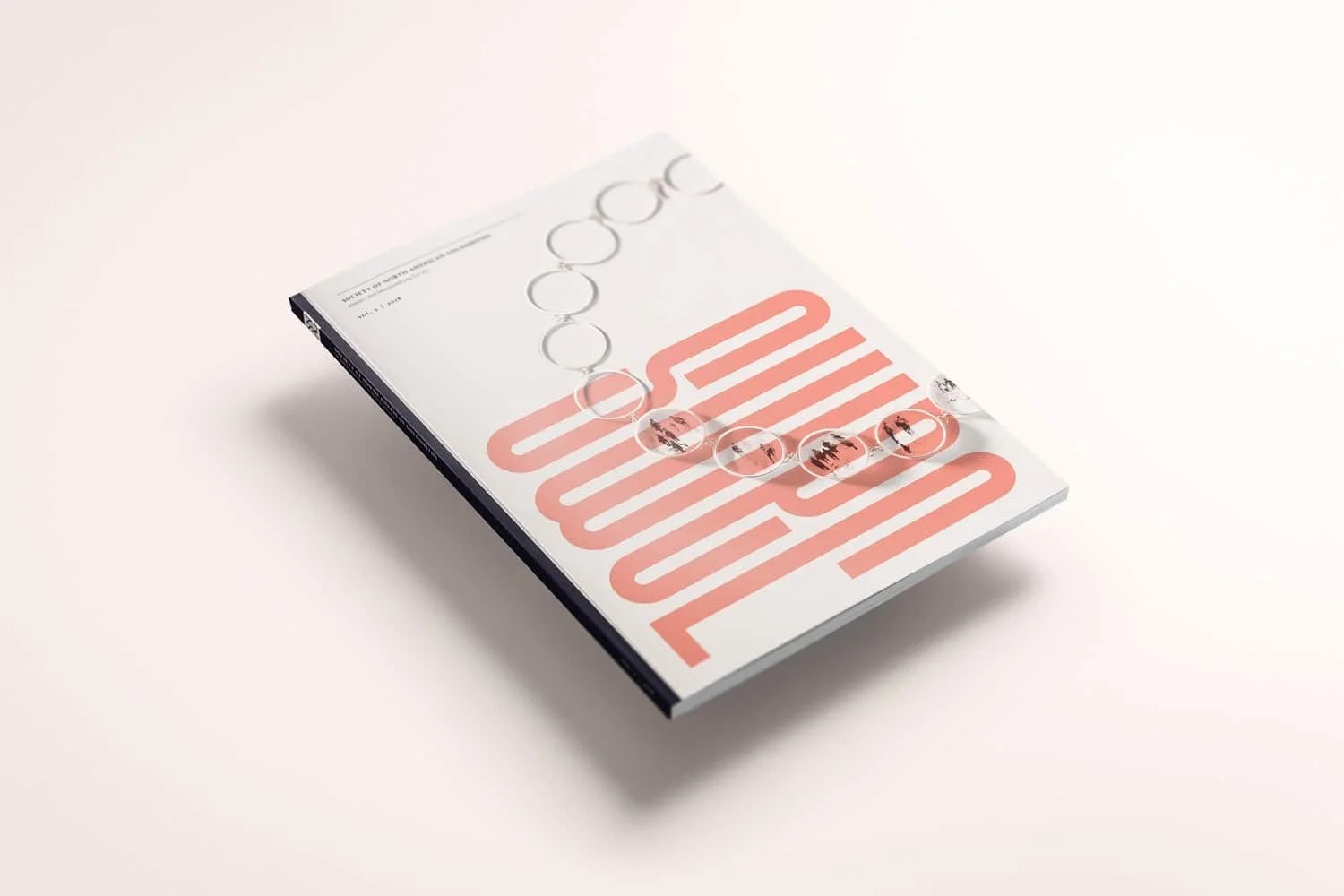 A magazine with a pink and white cover featuring abstract shapes and text, with a clear beaded necklace draped over it, placed on a white surface.