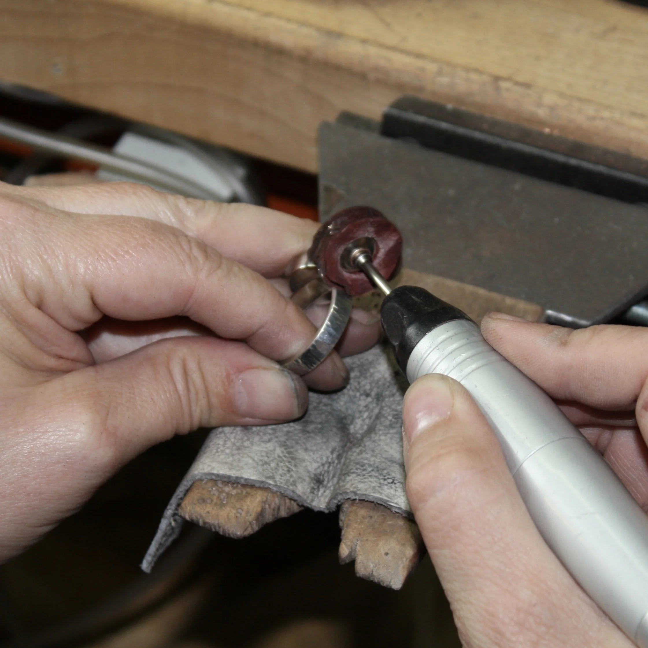 Jeweler using a flex shaft to polish the outside of a silver ring.