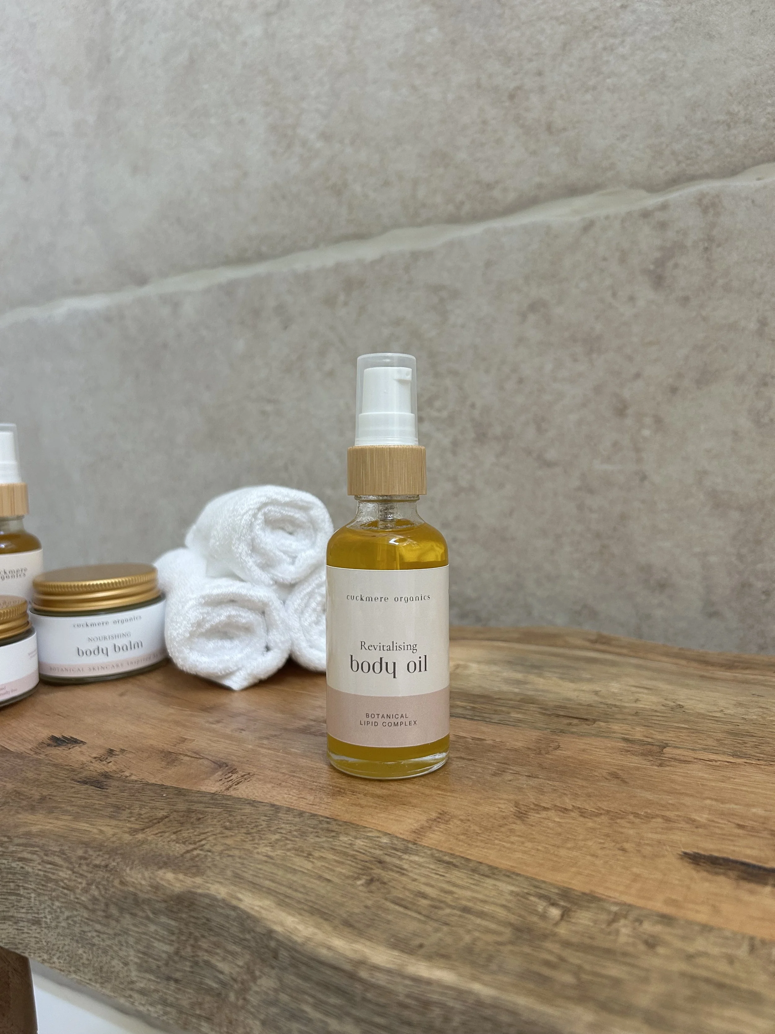 Cuckmere Organics Revitalising Body Oil on wooden board in a bathroom setting