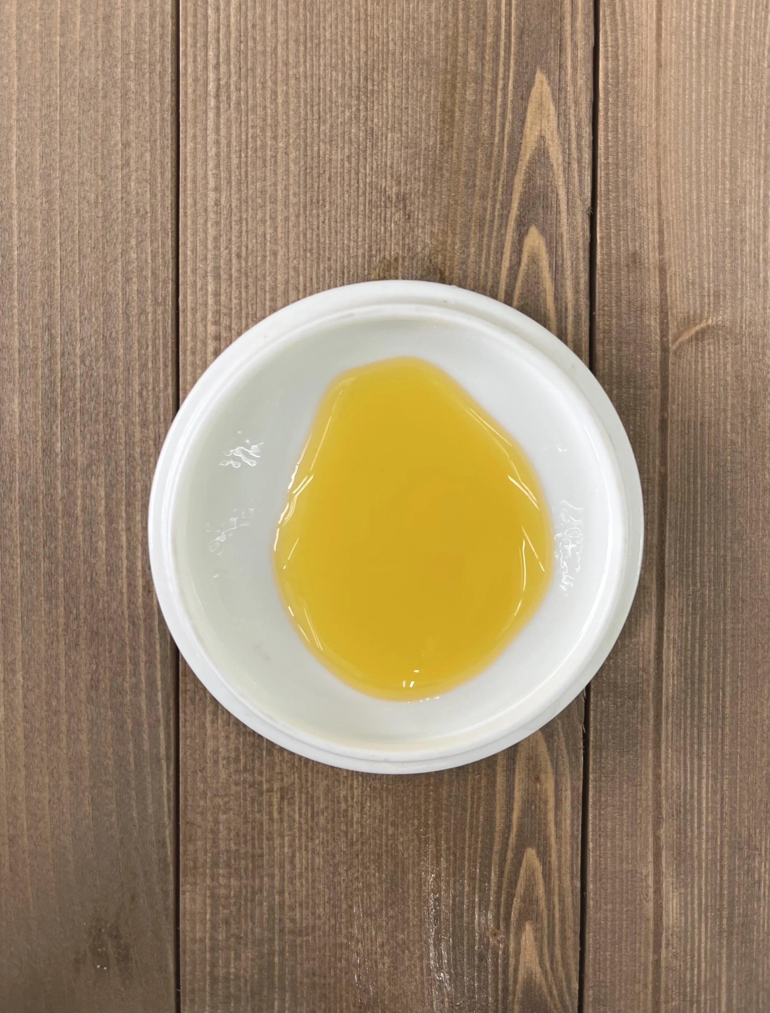 Golden botanical face serum oil texture in a ceramic dish