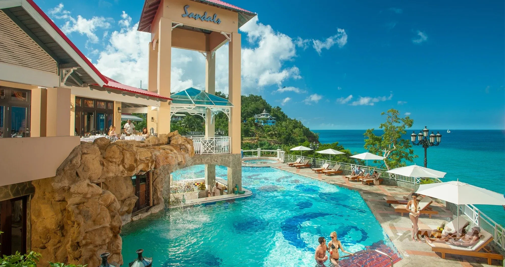 Sandals Regency La Toc resort pool with ocean views and lush greenery.