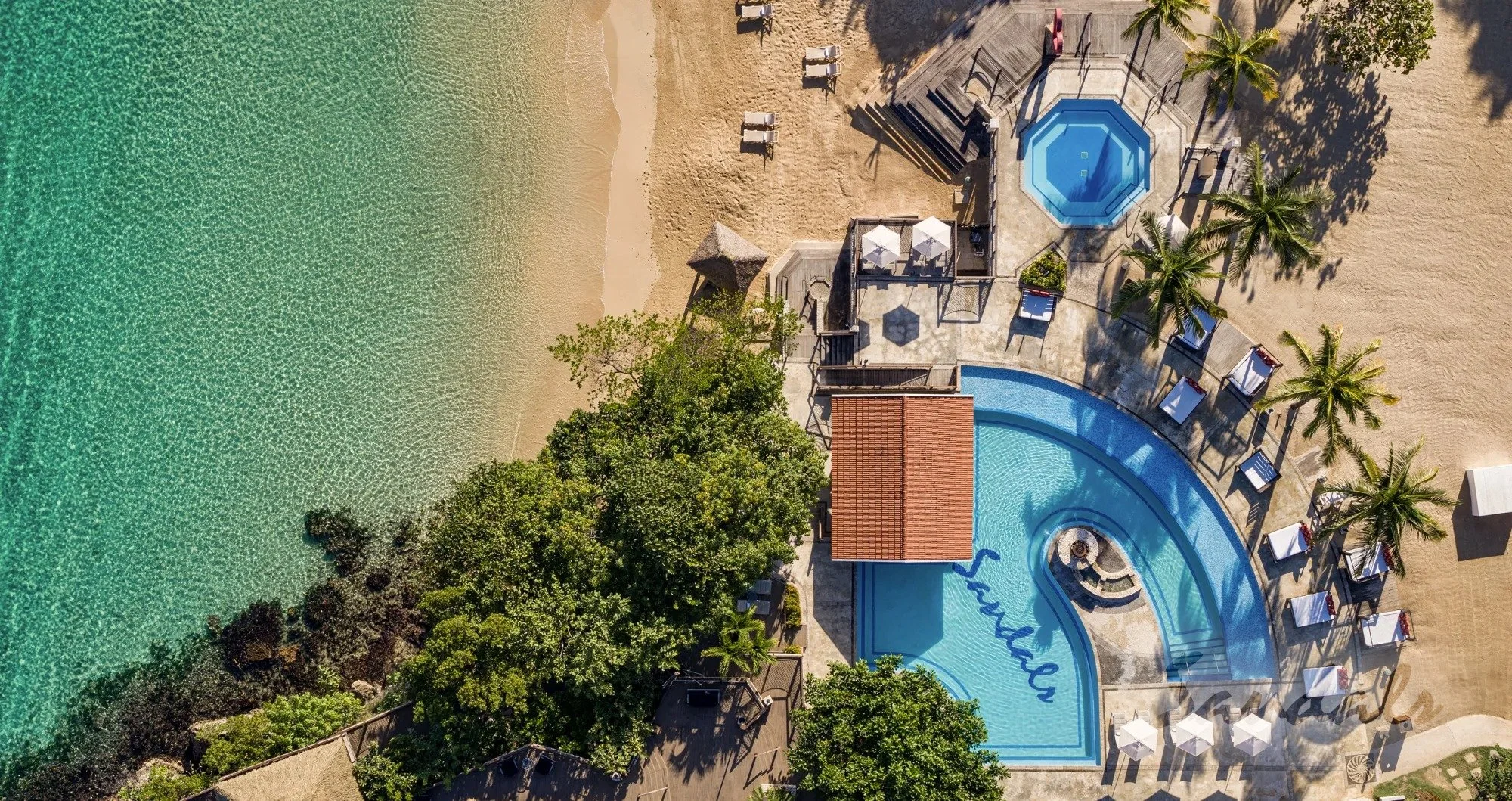 Ariel view of Sandals Ochi beach and pool.  You can see the swim up bar, lounge chairs, hot tub, and lucious trees