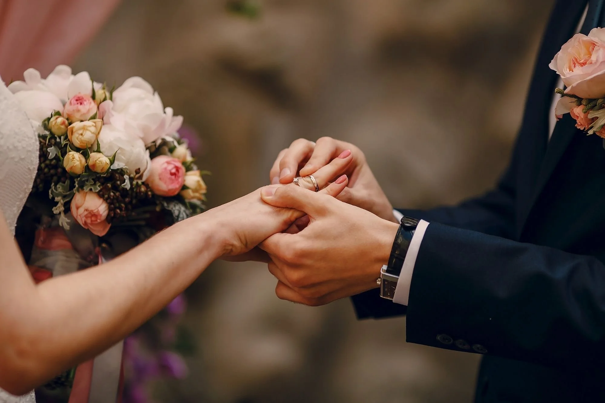 close-up of groom placing wedding ring on bride’s finger during ceremony