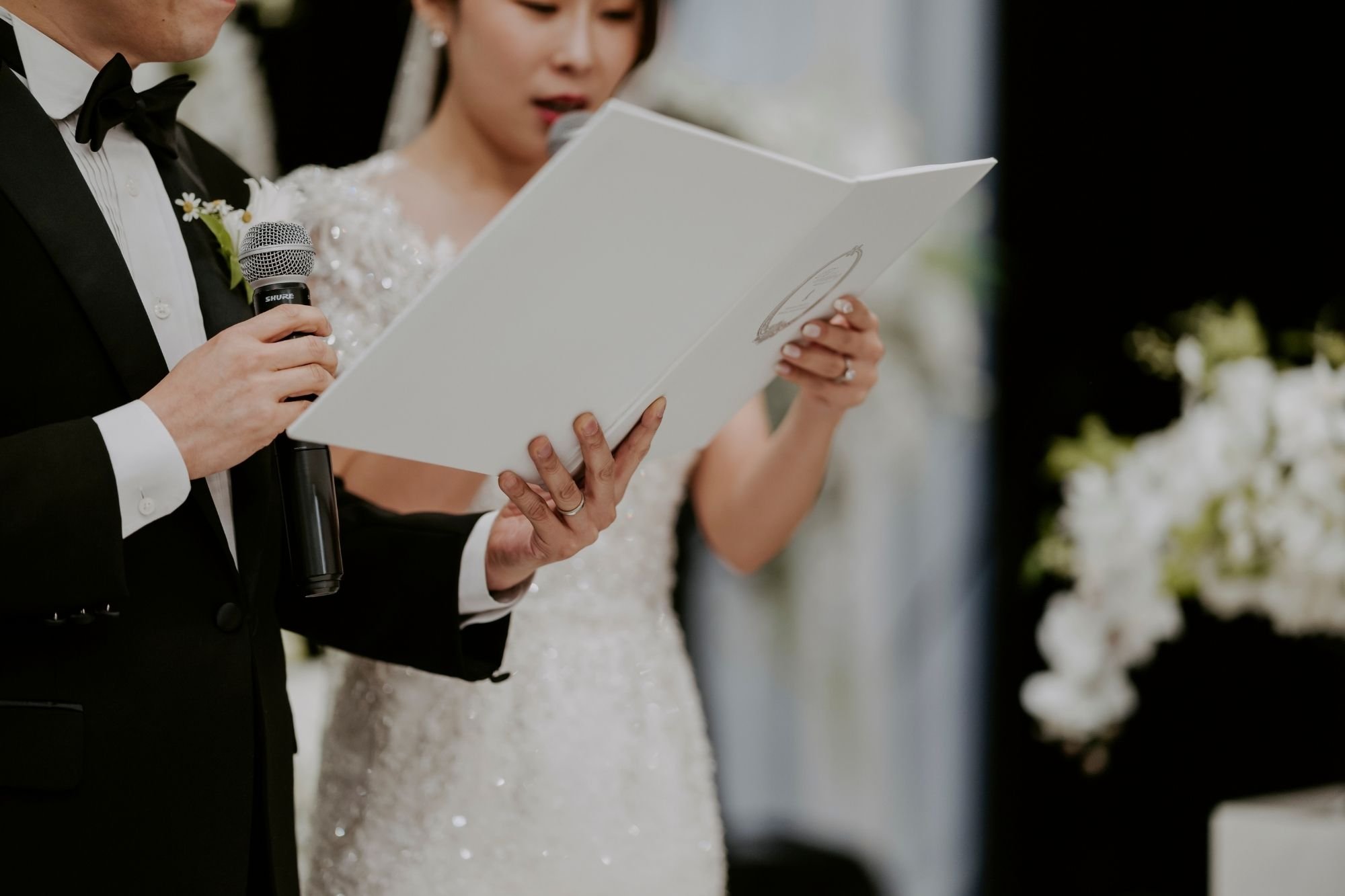Couple reading vows from a booklet with a microphone.