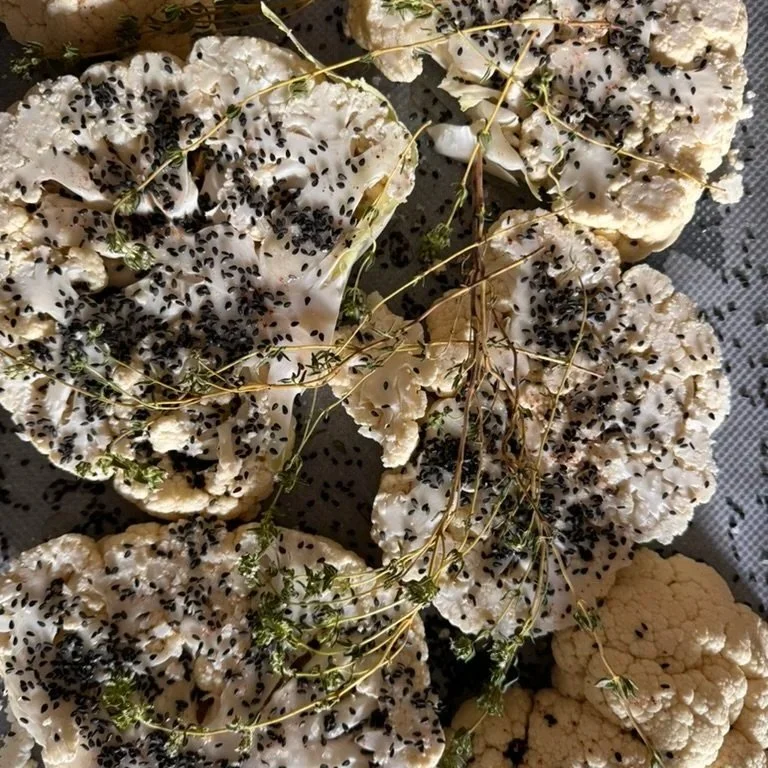 Cauliflower florets topped with black sesame seeds, garnished with sprigs of thyme.
