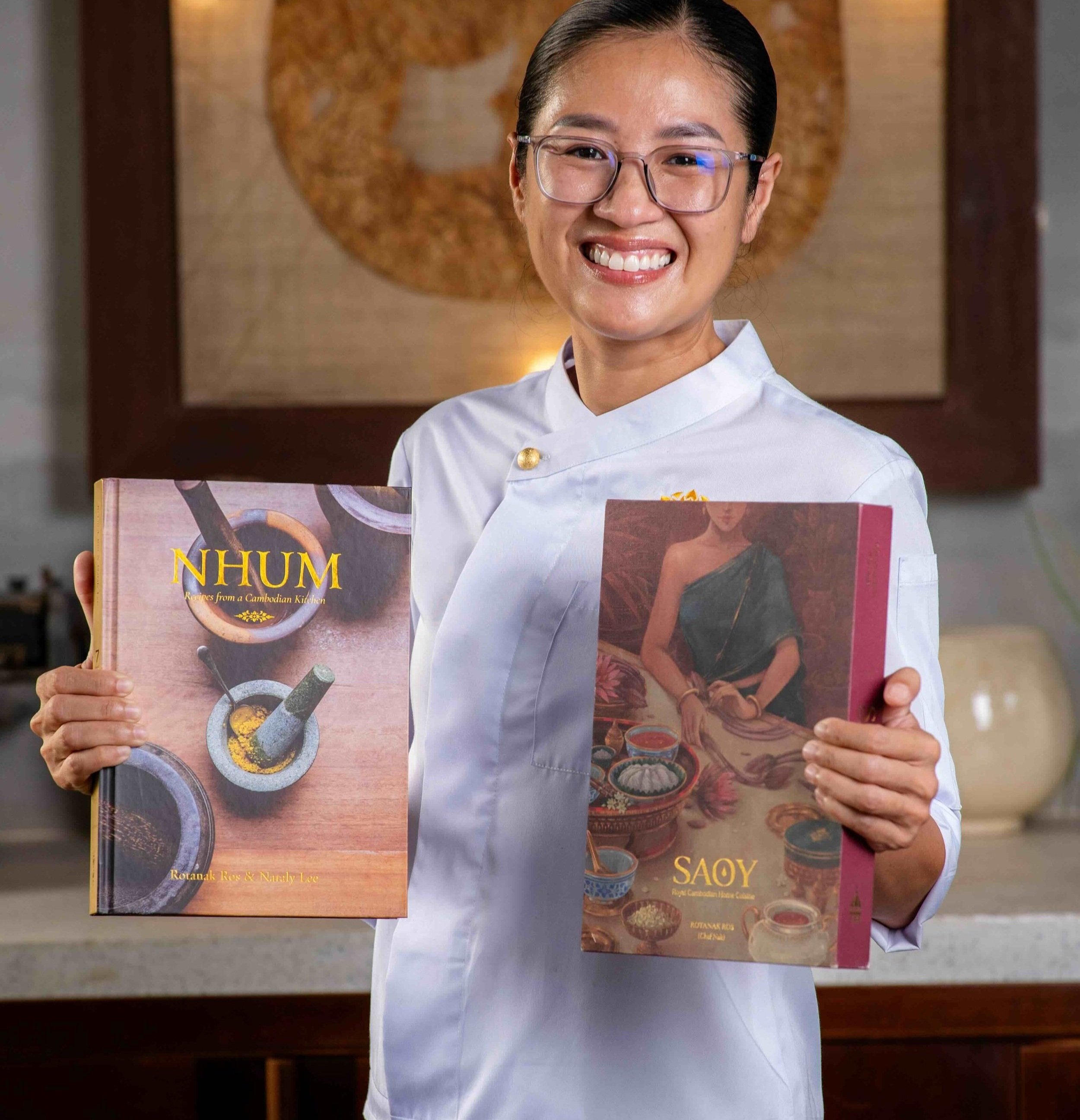Chef Nak holding her two Cambodian cookbooks, NHUM and SAOY.