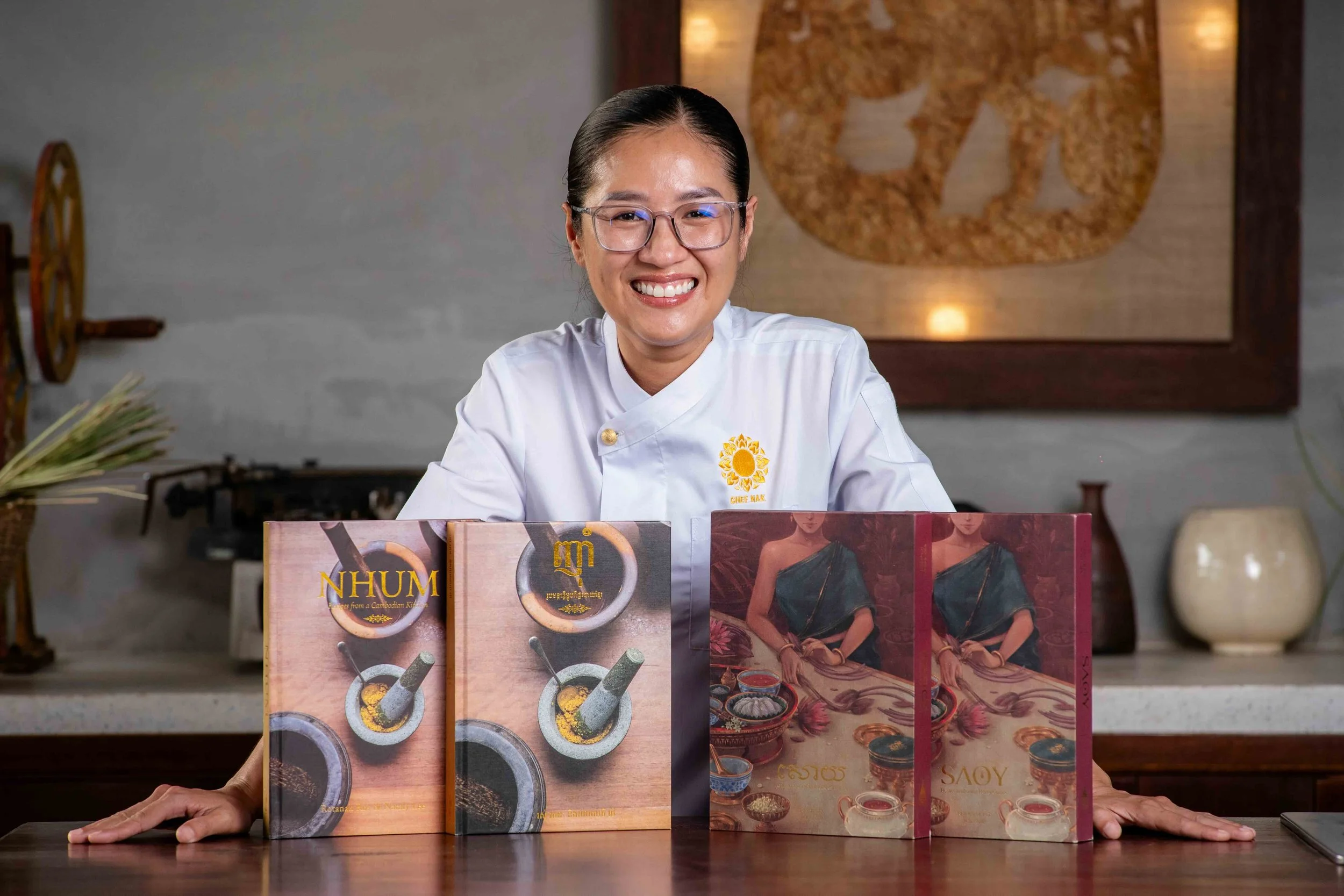 Chef Nak holding her two celebrated Cambodian cookbooks, NHUM and SAOY.