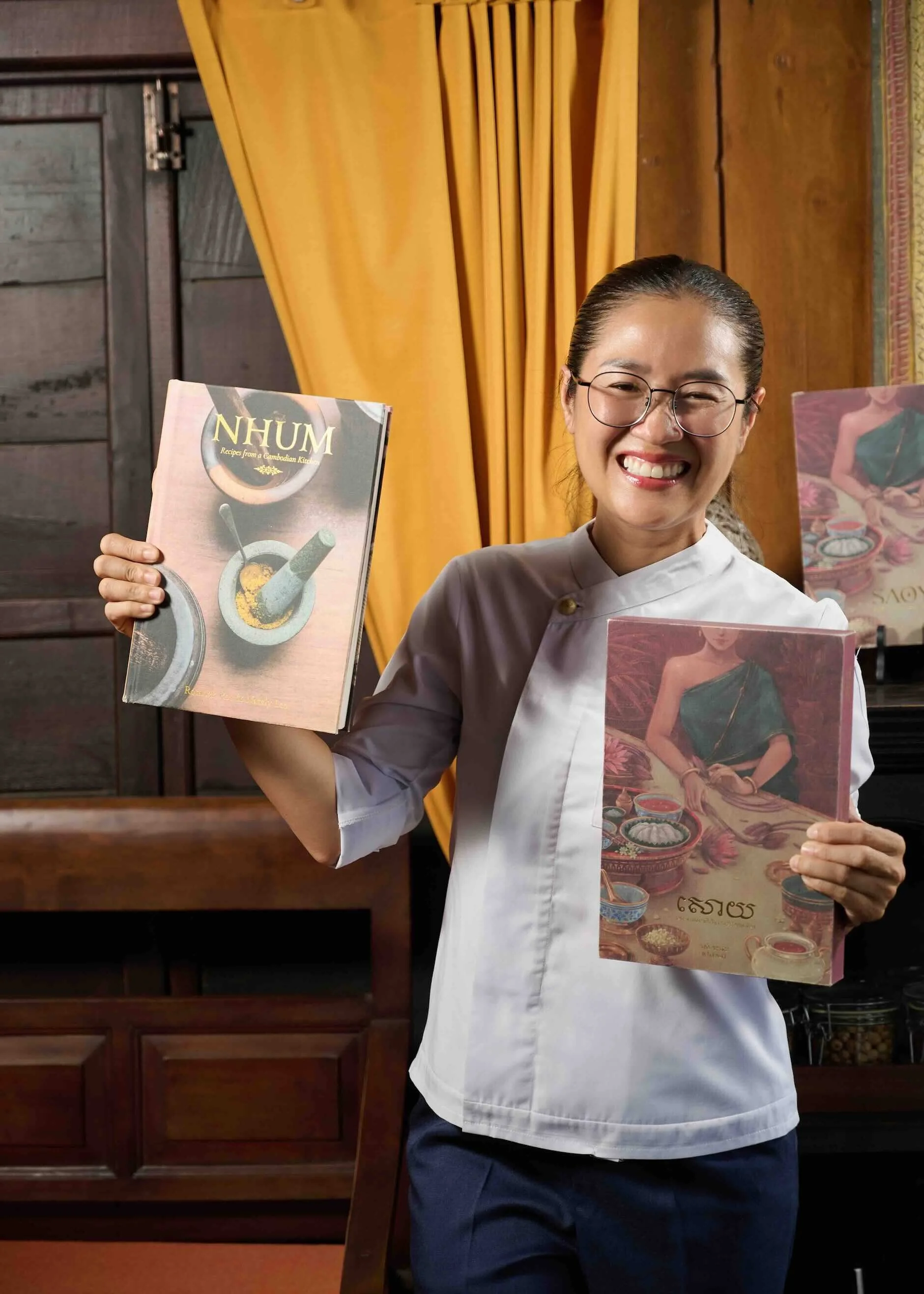 Chef Nak holding her Cambodian cookbooks, NHUM and the award-winning SAOY.