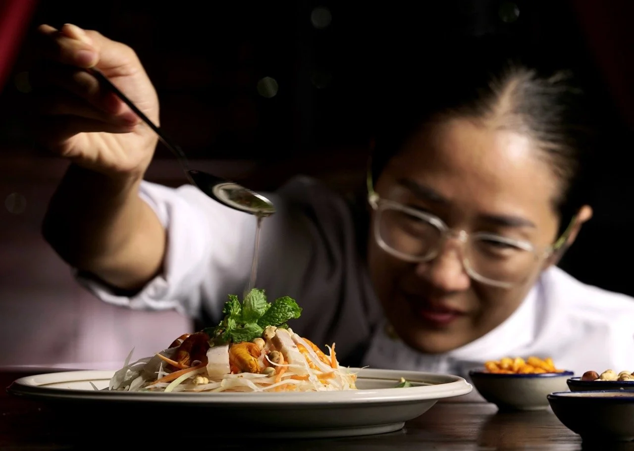 Chef Nak preparing a traditional Khmer papaya salad using fresh Cambodian ingredients.