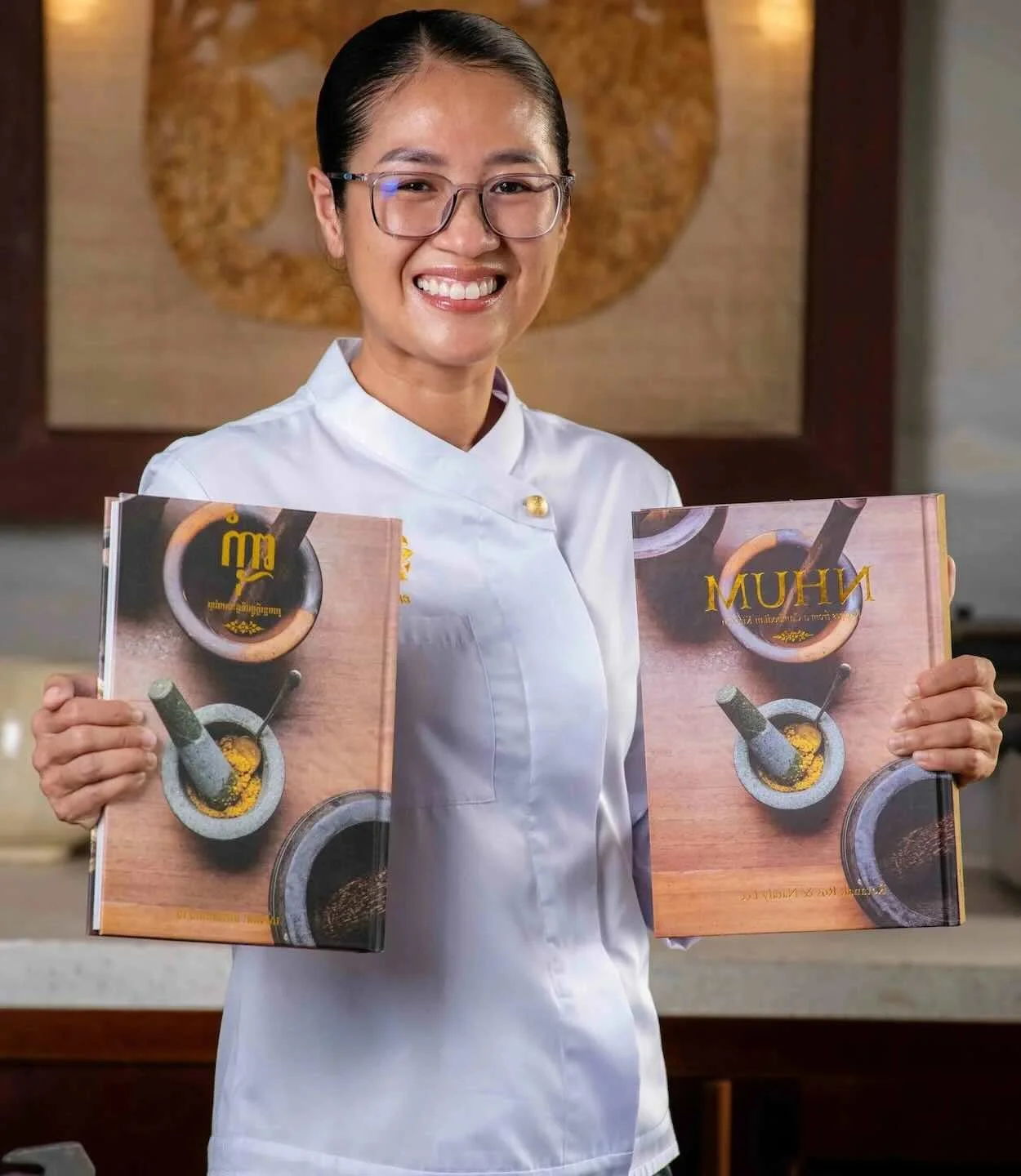 Chef Nak holding her Cambodian cookbook, NHUM.