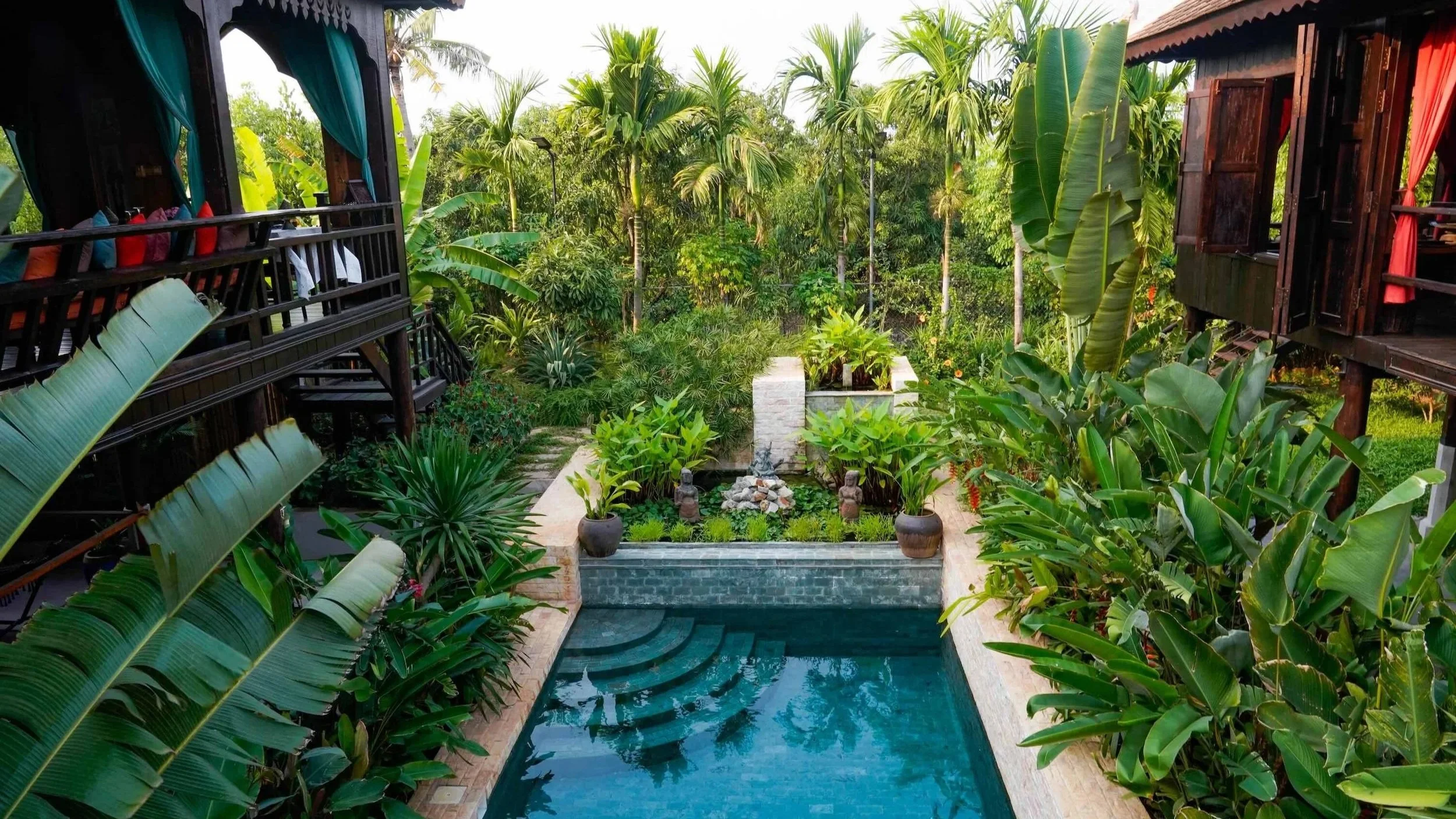 Lush tropical garden and swimming pool at Chef Nak’s cultural stay, surrounded by greenery and historic wooden houses