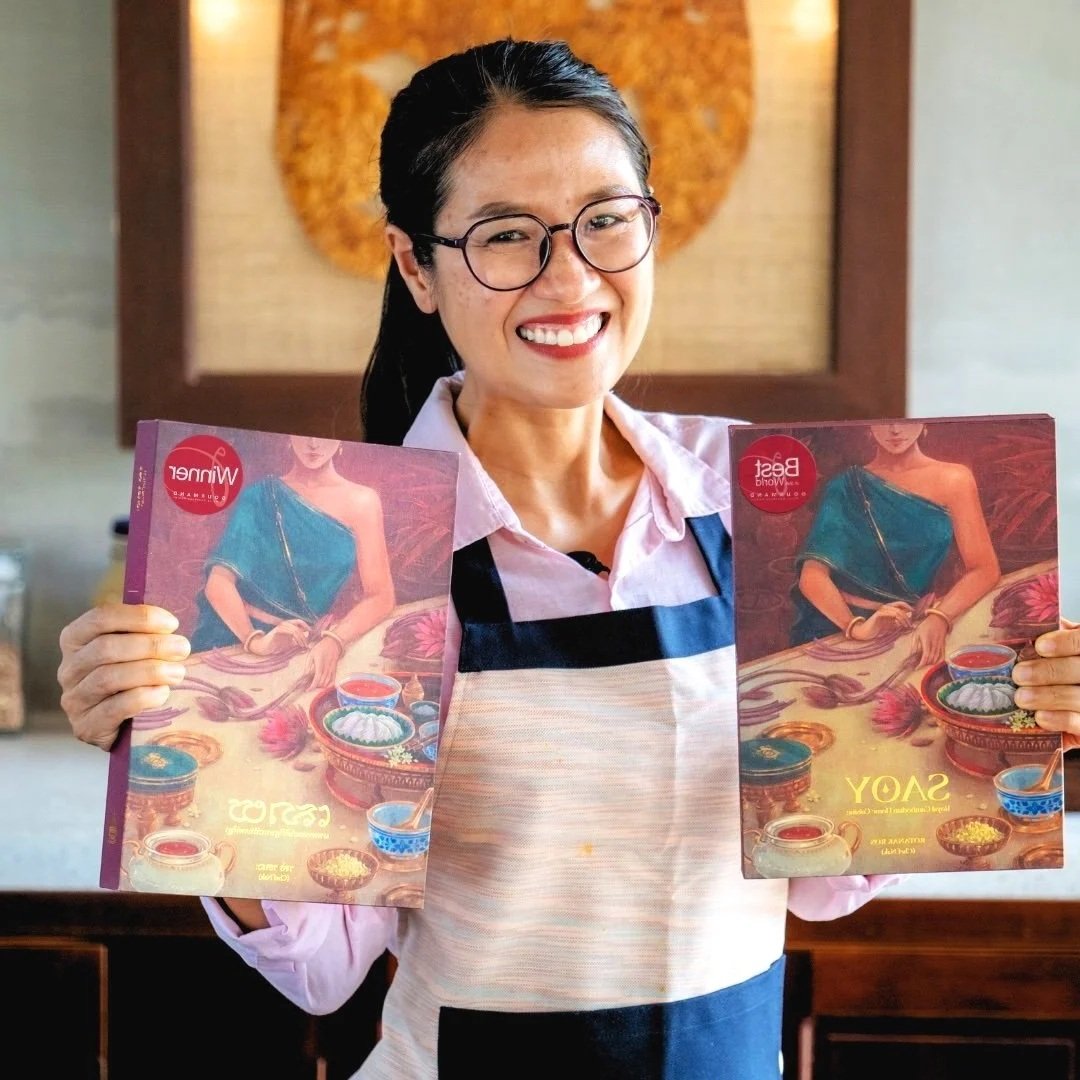 Chef Nak holding her award-winning Cambodian cookbook, SAOY
