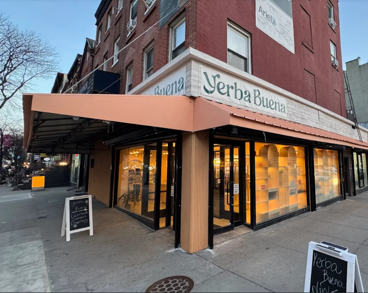 A photo of the exterior of the Yerba Buena Cobble Hill location, showing the beauty and poise of the exterior of the store at open, including an awning styled after the Italian architecture found in by the residence of the Dominican Founders.