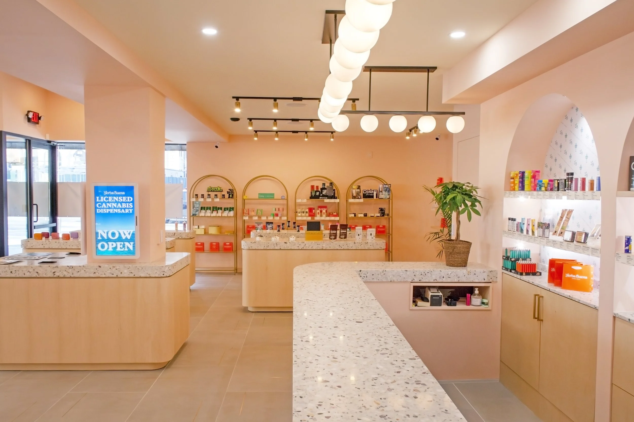 A photo of the Yerba Buena cobble hill interior, facing perpendicular to the checkout counter, showing beautiful architecture and products on the walls in a warm and welcoming atmosphere.