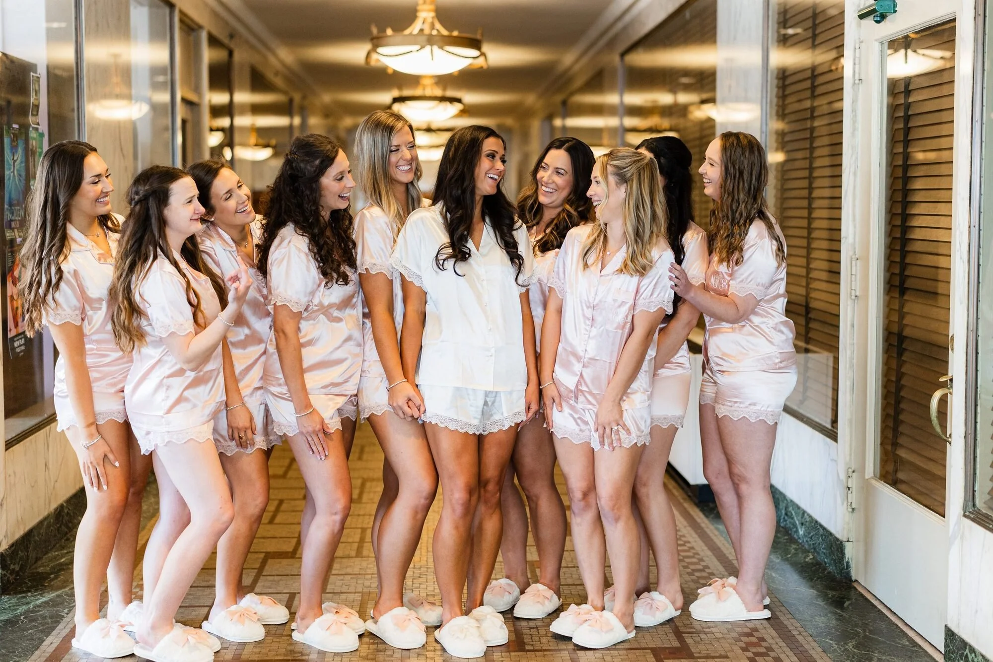 Bride and bridesmaids laughing in matching pajamas in a Westin Poinsett hallway