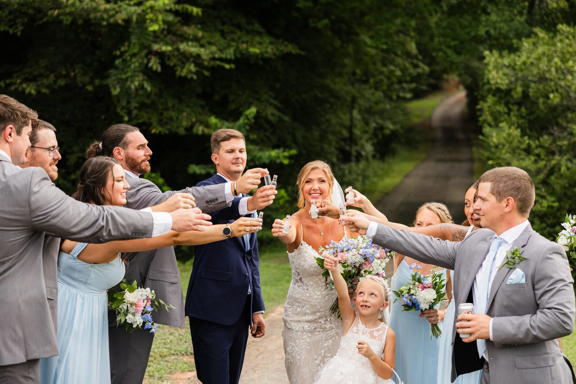 Wedding party raising a toast on the wooded lane at Greenbrier Farms in Easley, SC