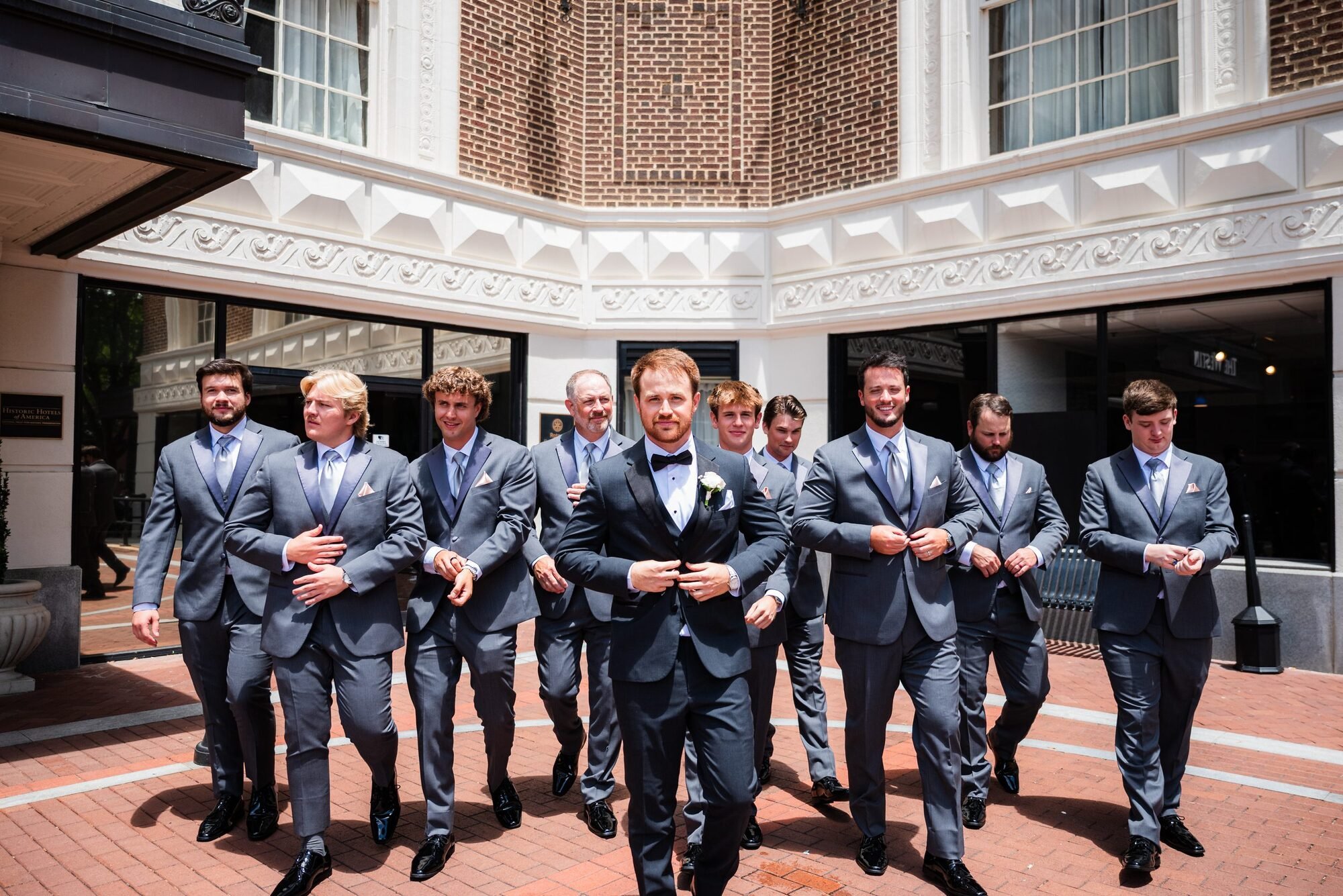 Groomsmen laughing and fixing the groom's jacket outside the Westin Poinsett