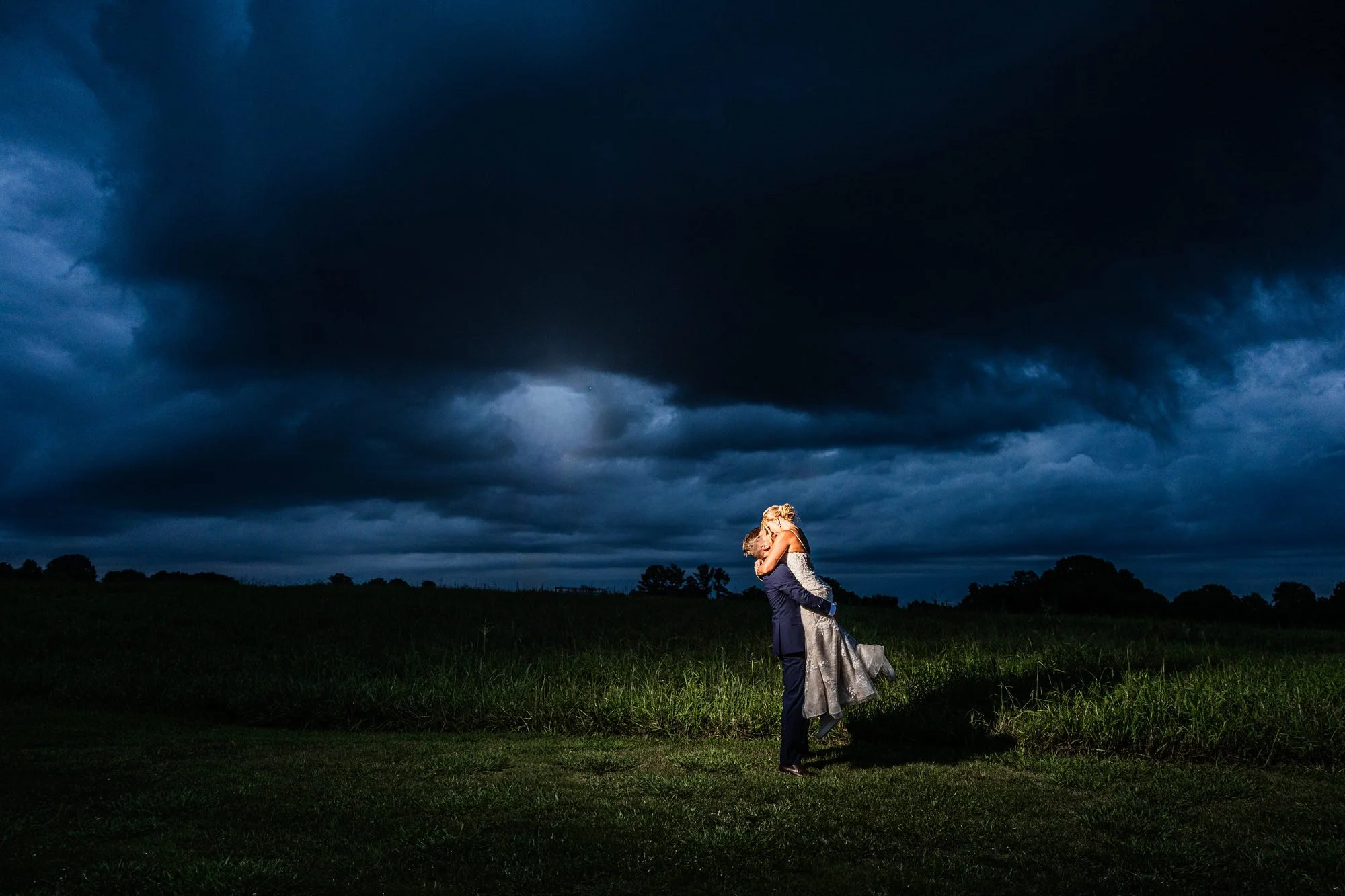 Bride and groom in an open field under storm clouds at Greenbrier Farms in Easley, SC