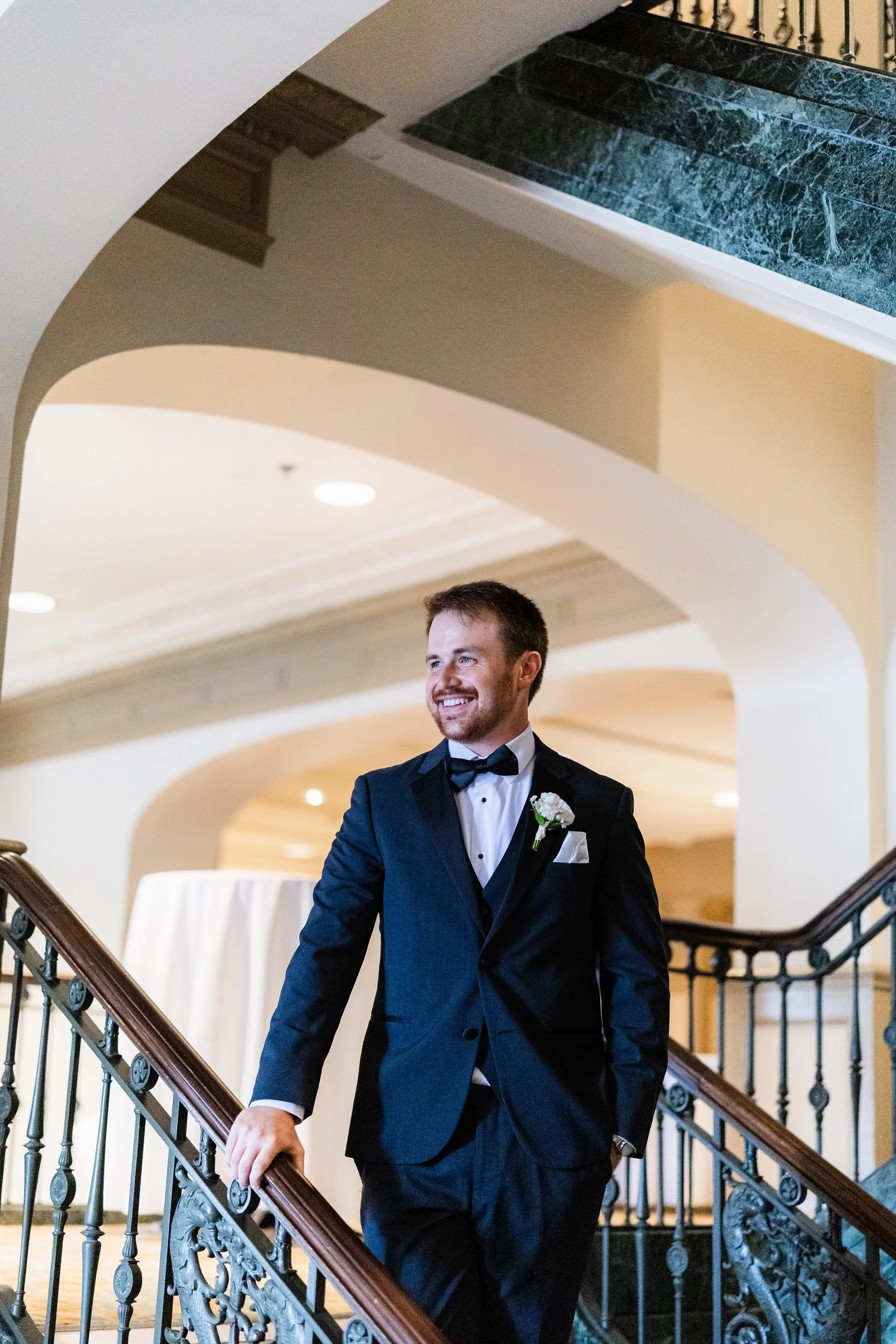Groom on the marble staircase with iron railing inside the Westin Poinsett