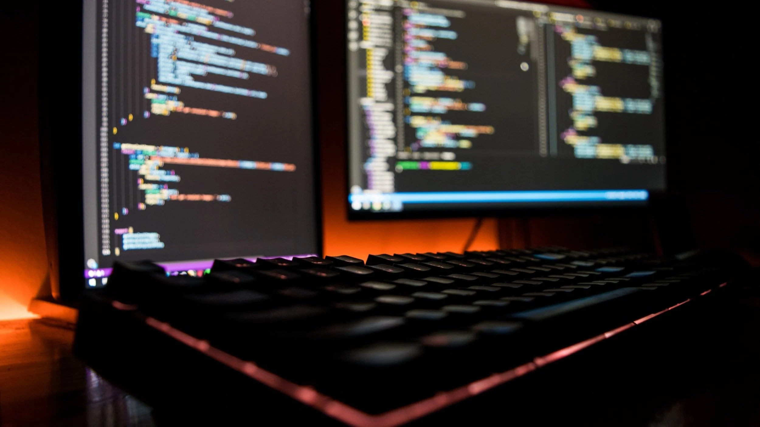 Software Audits Don’t Have To Be A Pain: photo of two computer screens displaying code in a dark room