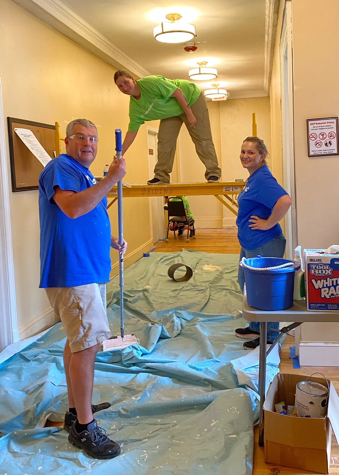 Three volunteers paint a hallway at GAP Ministries.