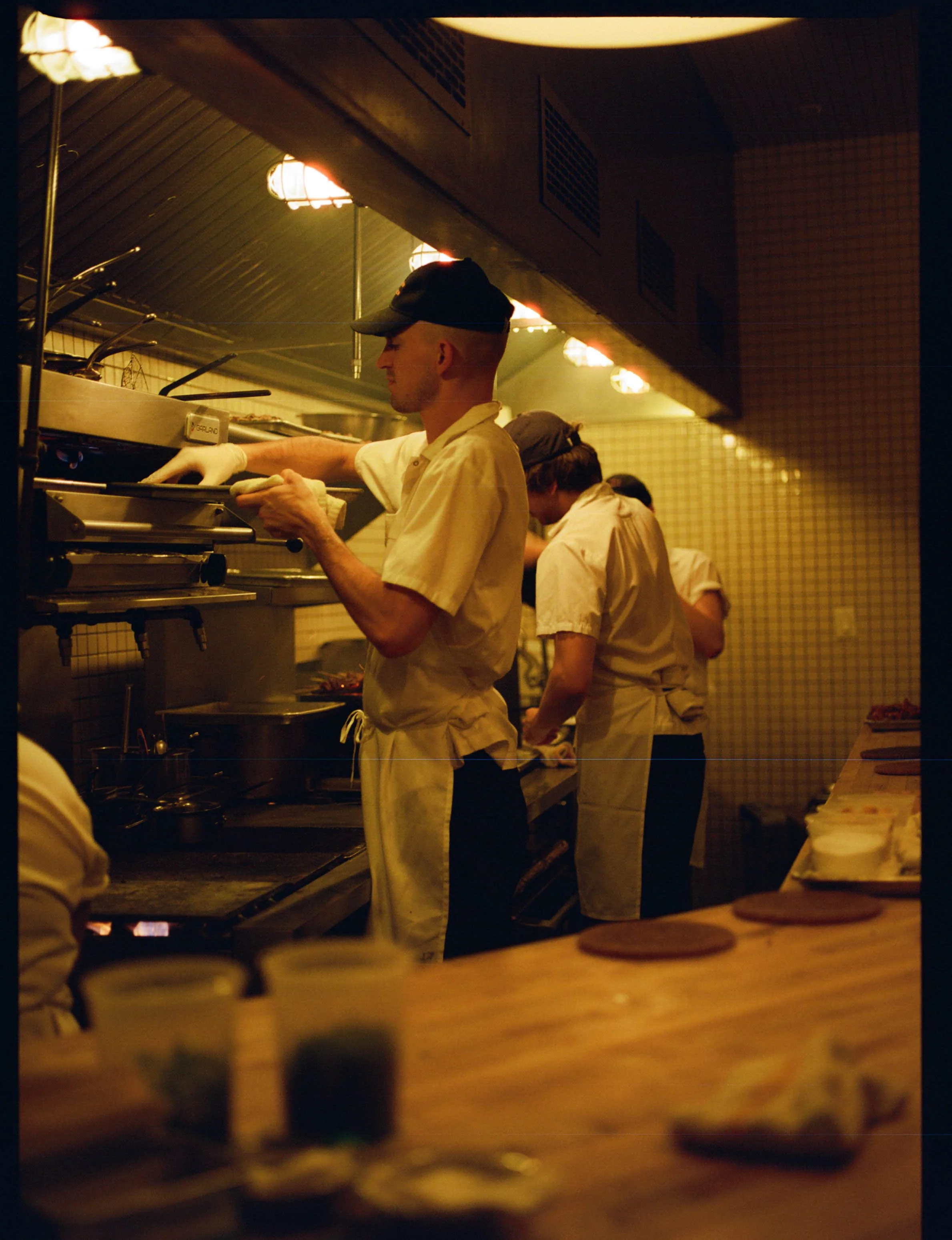 Kitchen staff preparing food in a restaurant kitchen with warm lighting.