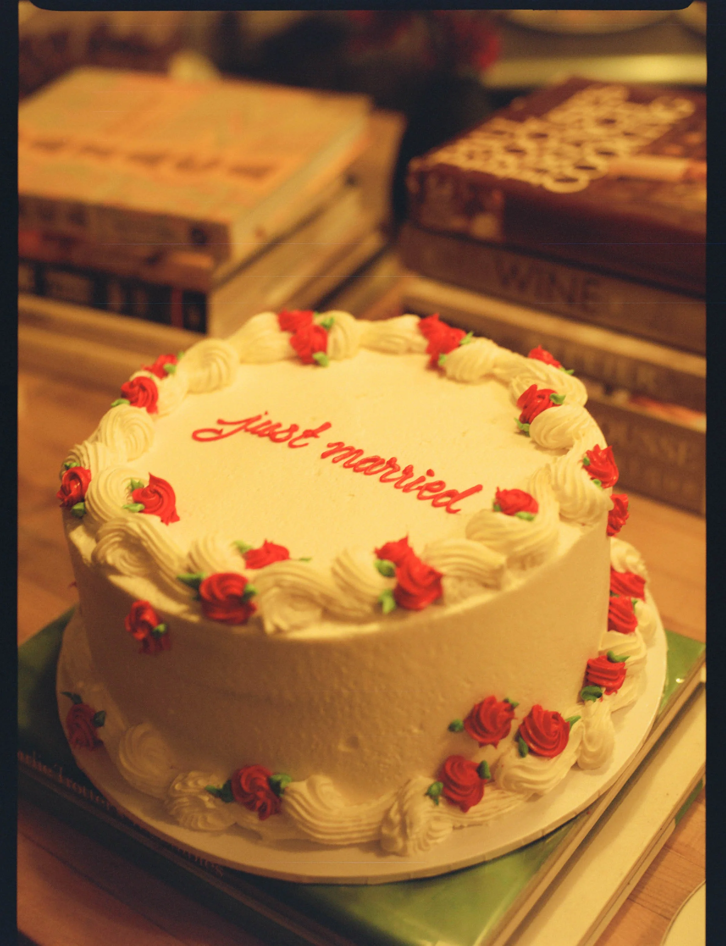 Round white cake decorated with red and white frosting roses and the words "just married" written in red icing.
