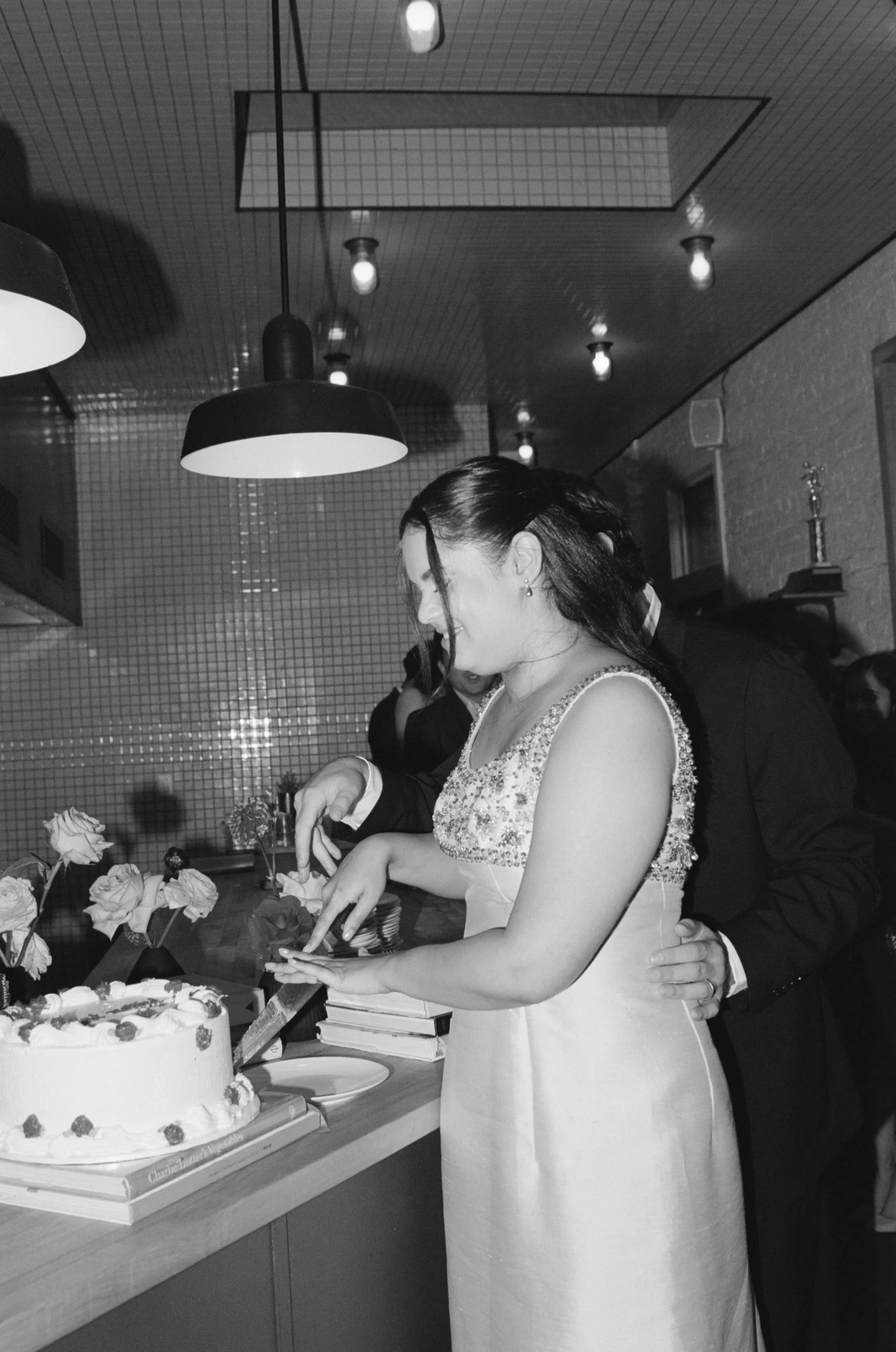 Bride and groom cutting wedding cake at reception in a decorated indoor venue.