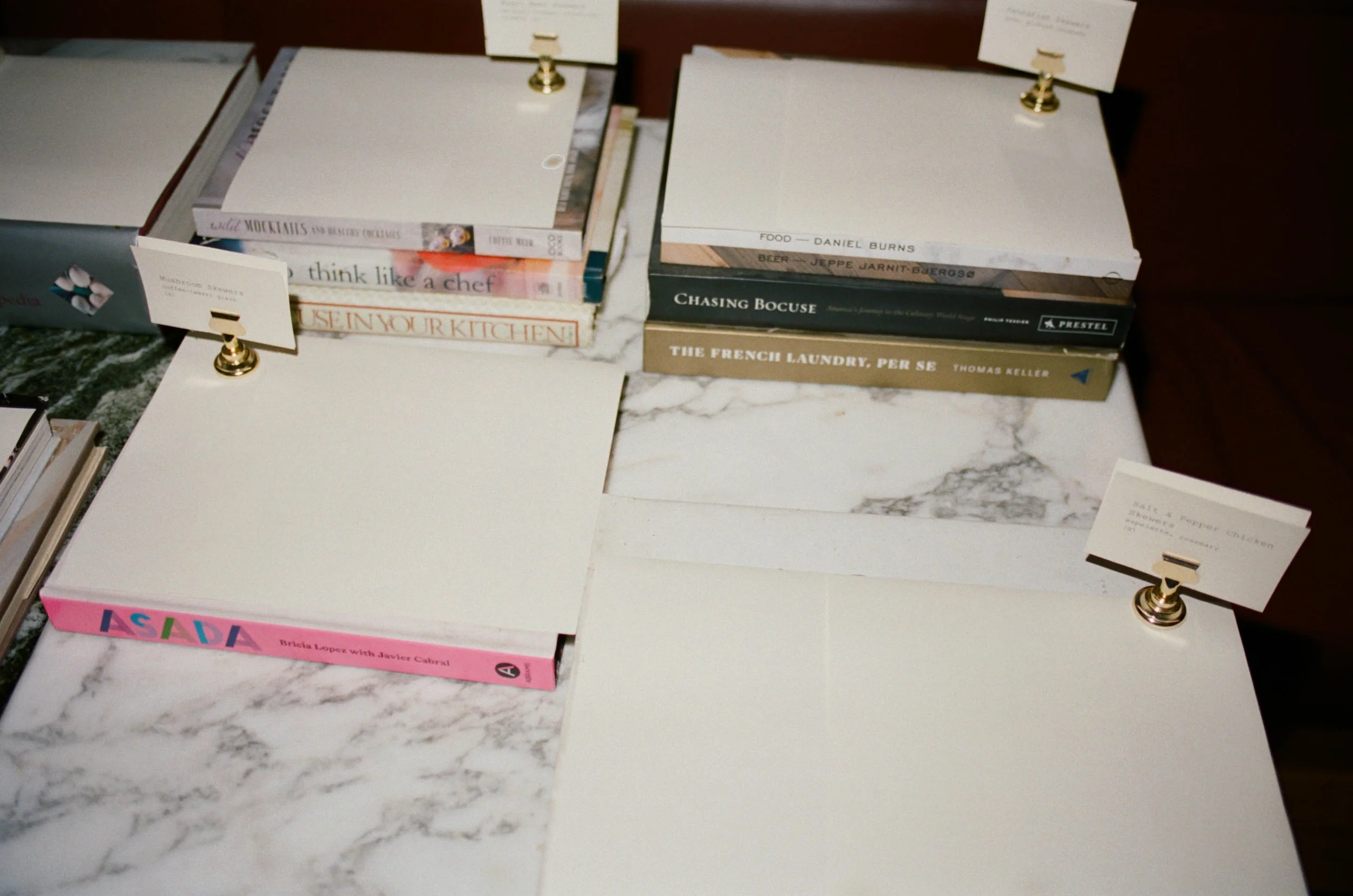 Stack of books on a marble counter with small signs clipped to metal holders.