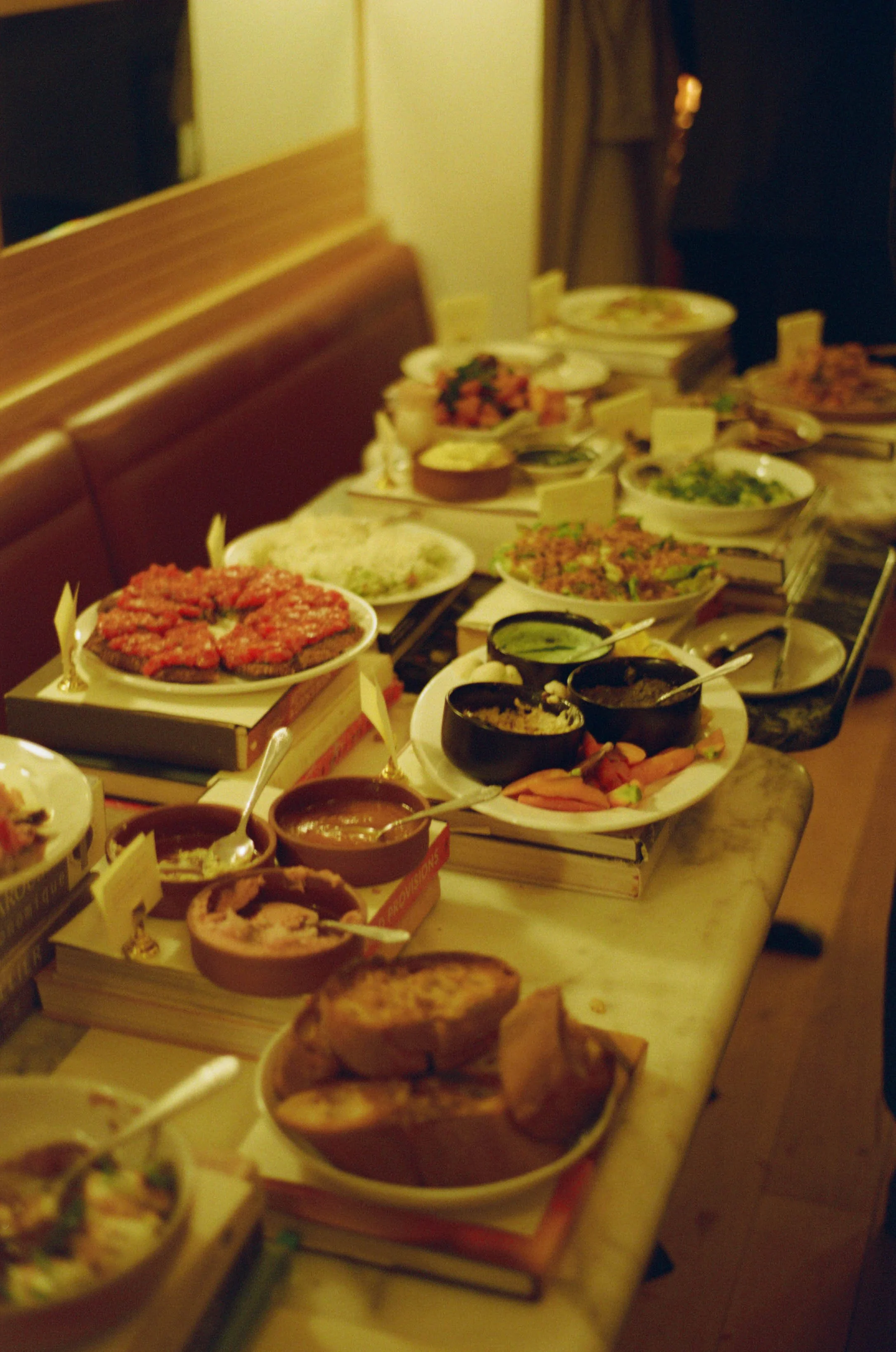 A variety of dishes, bowls, and plates filled with different foods on a long table in a restaurant.